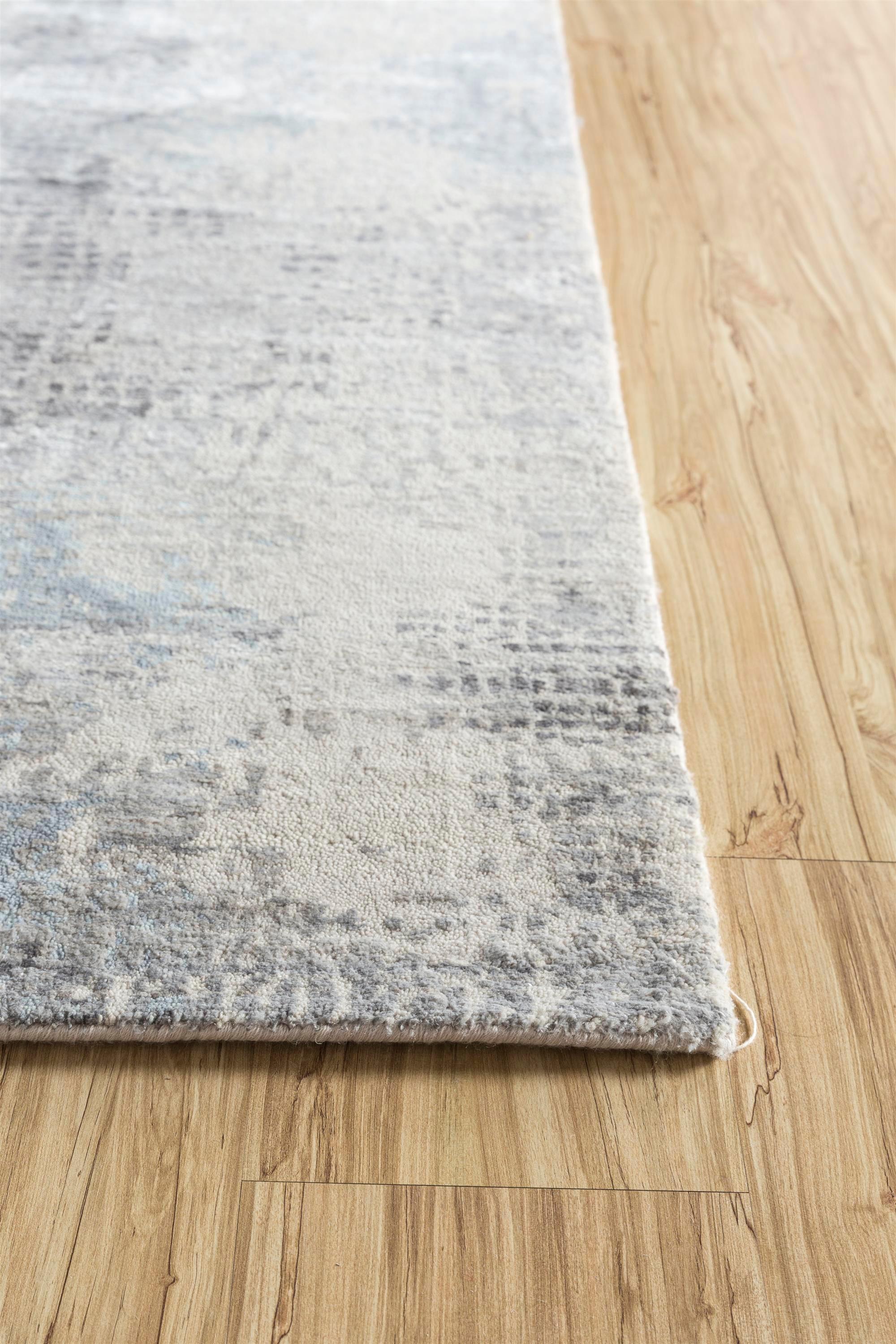 Dive into the unseen beauty of the creative process with this hand-knotted rug from rural India. Inspired by the unnoticed marvels of development and perpetual motion, this modern masterpiece  features an antique white base and a pearl blue border.