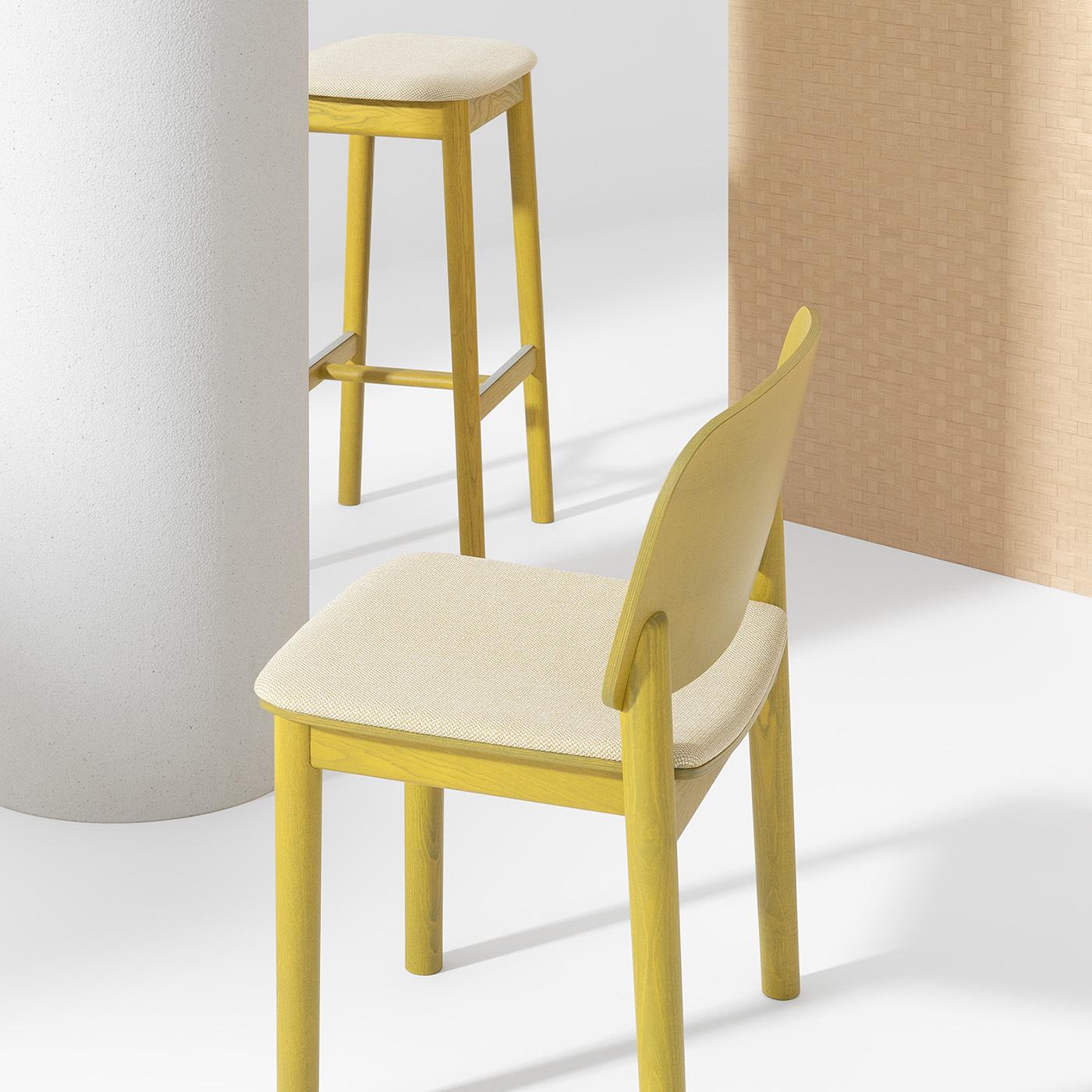 This fine chair designed by Harri Koskinen emphasizes the charm of formal simplicity with a harmonious choice of chromatic tones. Top-rate ash lacquered in a vibrant curry tone is used to craft the unadorned frame, which includes the open, slightly