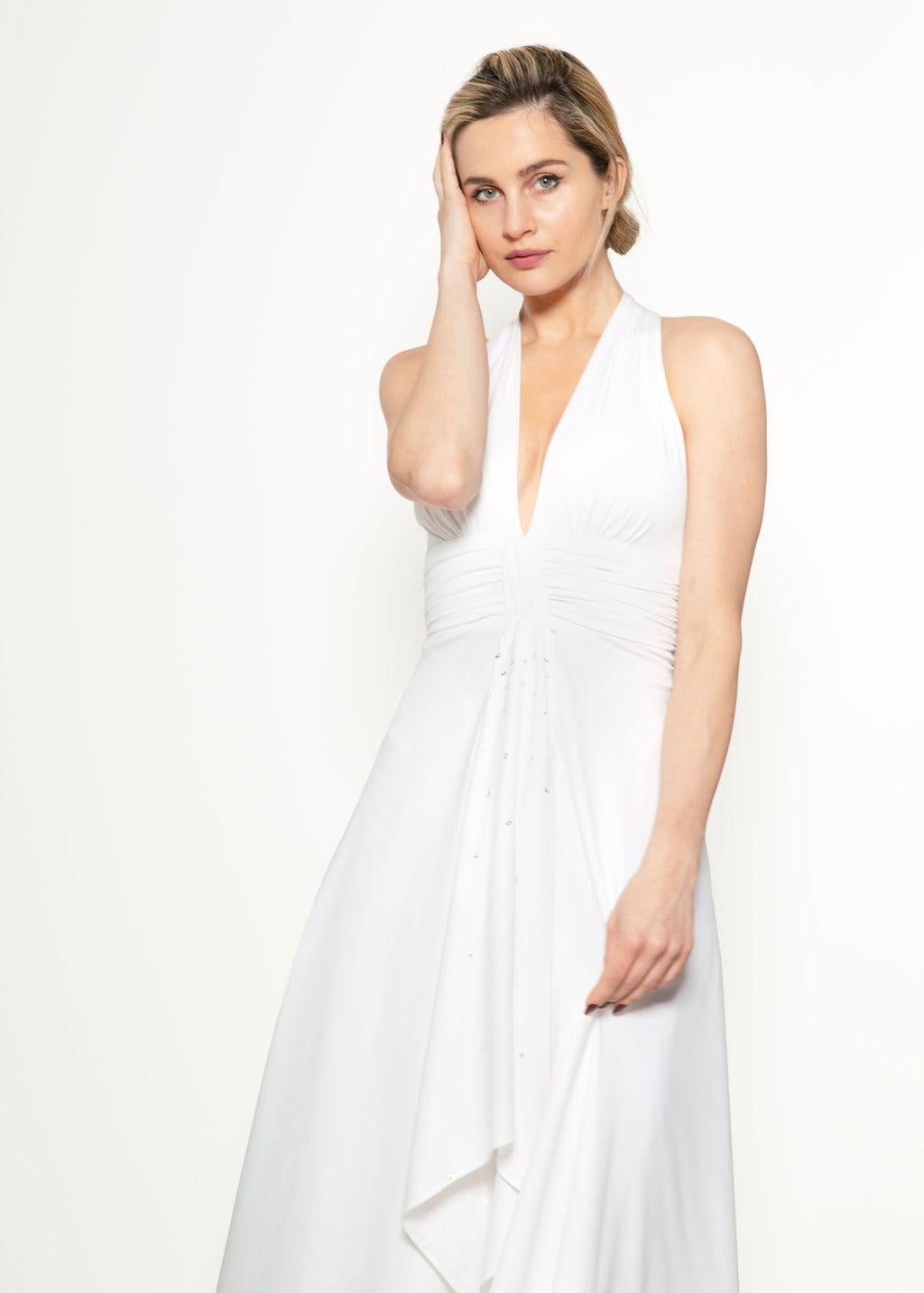 Get ready for your Marilyn Monroe moment! This elegant White 1970's Halter Dress is perfect for a bride to be or anyone looking for a striking and classic gown!

The dress features a deep v-neck neckline and a zipper in the back. Delicate sequin