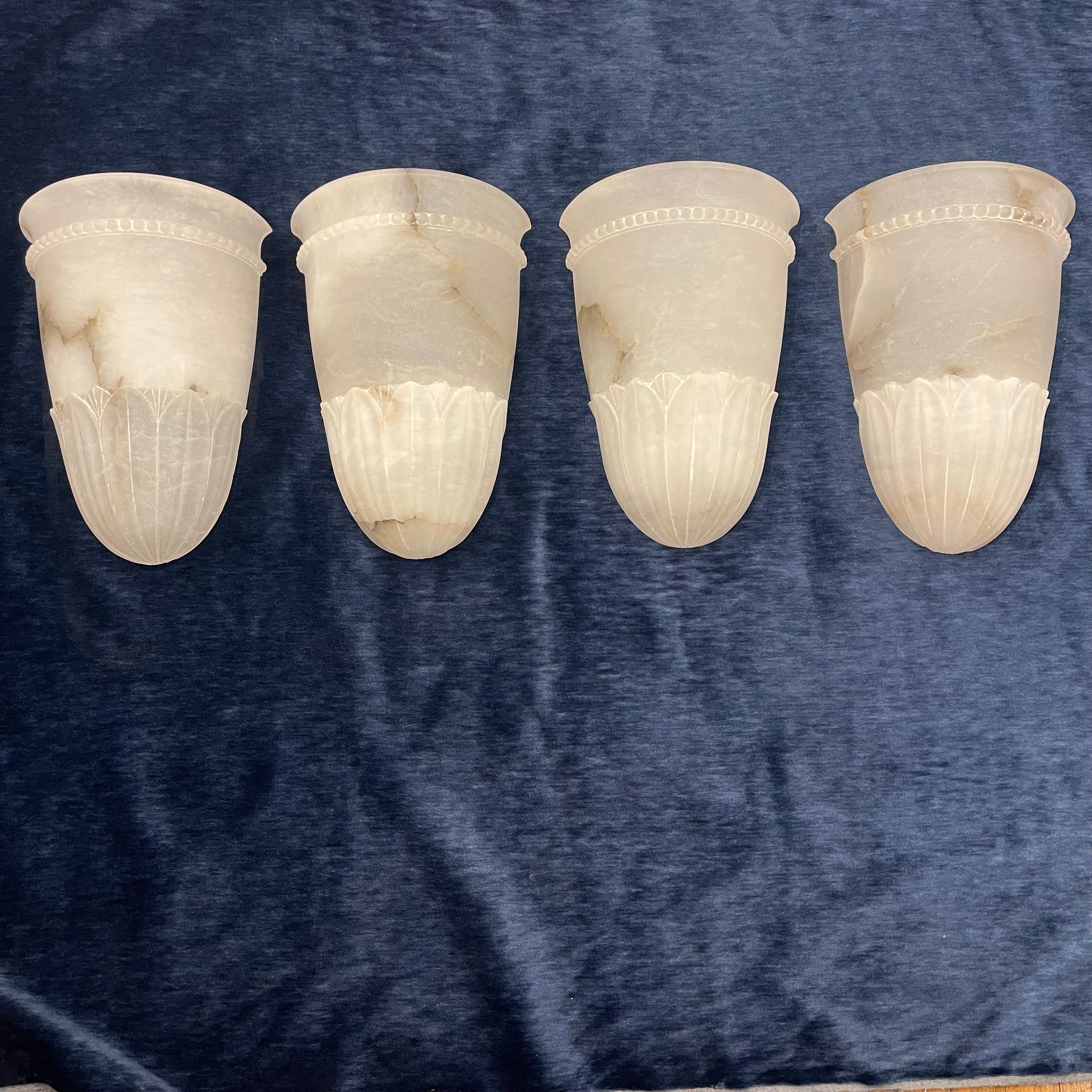 These urn shaped sconces, decorated with a base of acanthus leaves and trimmed with discrete beading are each carved from a single piece of ivory alabaster, with delicate black and grey veining. May also be purchased in pairs.