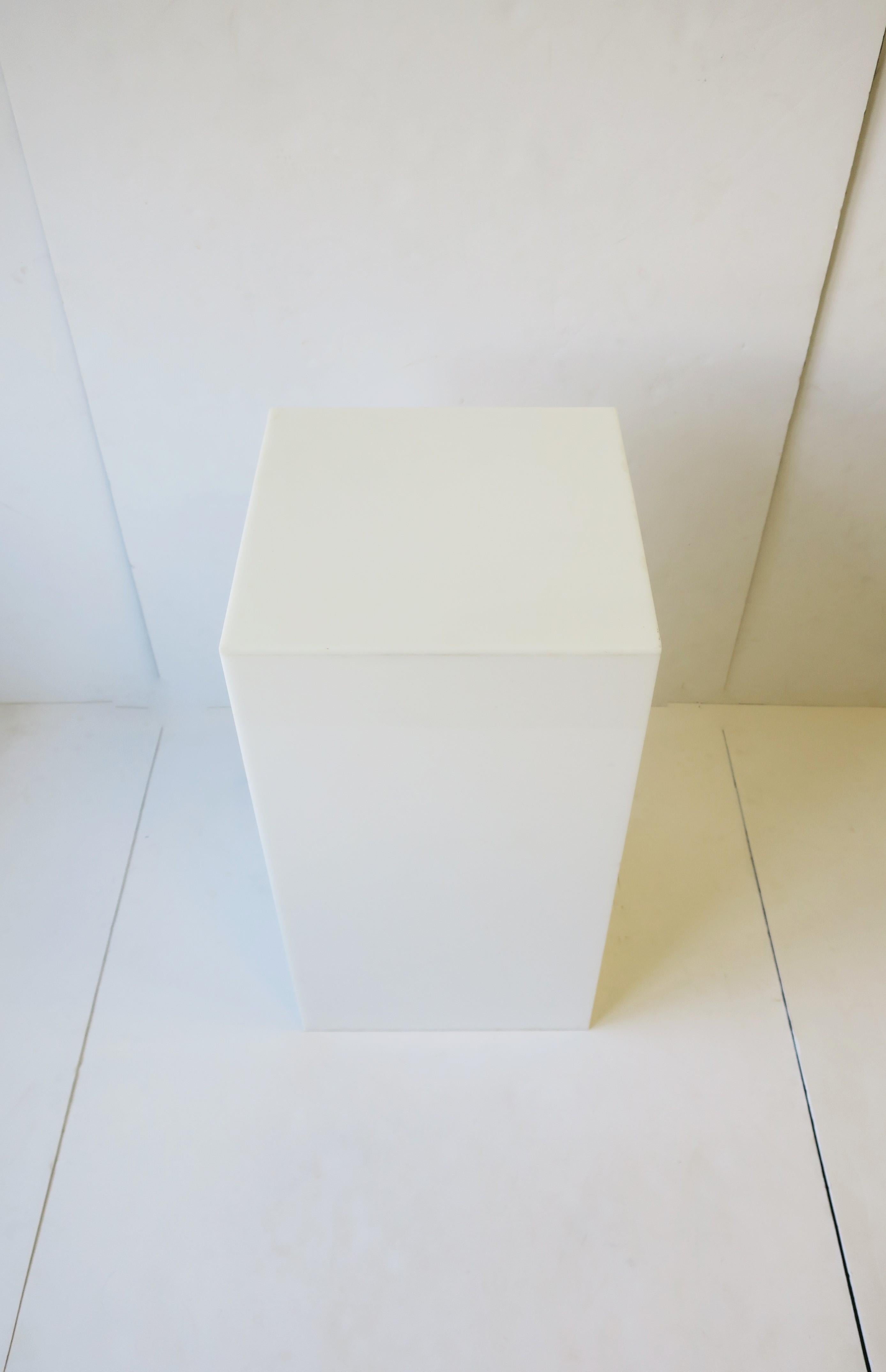 A modern or postmodern period white acrylic pedestal column stand display piece or end table, circa late 20th century. Great for items such as art, sculpture, jewelry display, plant, and more; Or as and end table as demonstrated with books and table