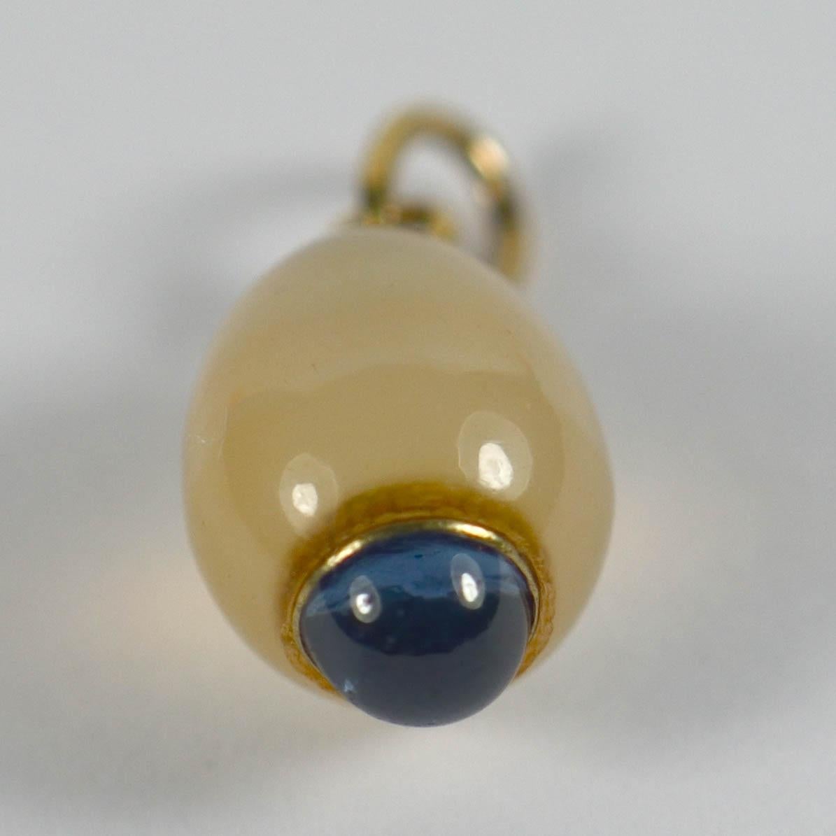 A French pendant charm designed as a creamy white carved agate egg with a cabochon of natural blue sapphire at the base. Mounted in 18 karat yellow gold with French import marks. 2/3