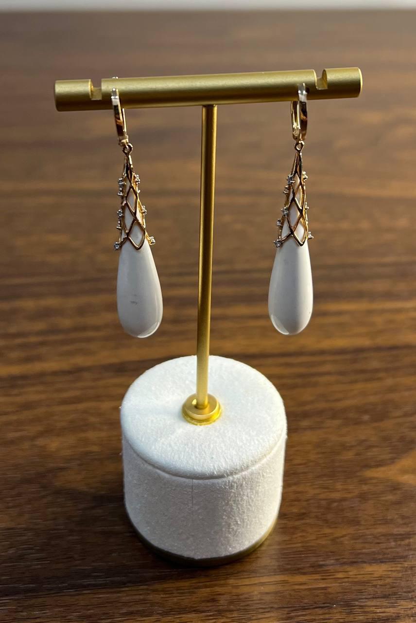 Questi sofisticati orecchini sono realizzati con un design delicato. Ogni orecchino presenta un'agata bianca a forma di goccia, levigata e sospesa con eleganza.
La pietra è racchiusa in un intricato reticolo d'oro, ornato da piccoli e scintillanti