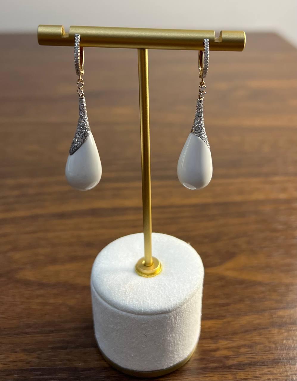 Orecchini a goccia in agata bianca e diamanti. Questo raffinato paio di orecchini presenta un elegante design a goccia con una finitura bianca liscia. La parte superiore è impreziosita da scintillanti accenti di diamanti, che aggiungono un tocco di