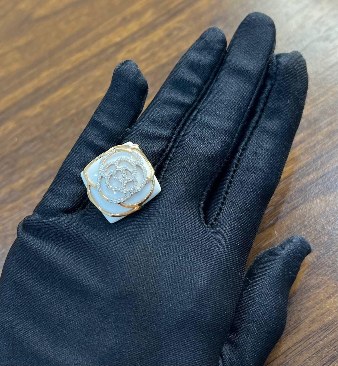 A study in elegance, form, and shimmer.

This captivating ring features a delicate 18K rose gold flower motif, intricately designed with sparkling diamond accents around a white agate gemstone. The rose is framed by a smooth, lustrous surface,