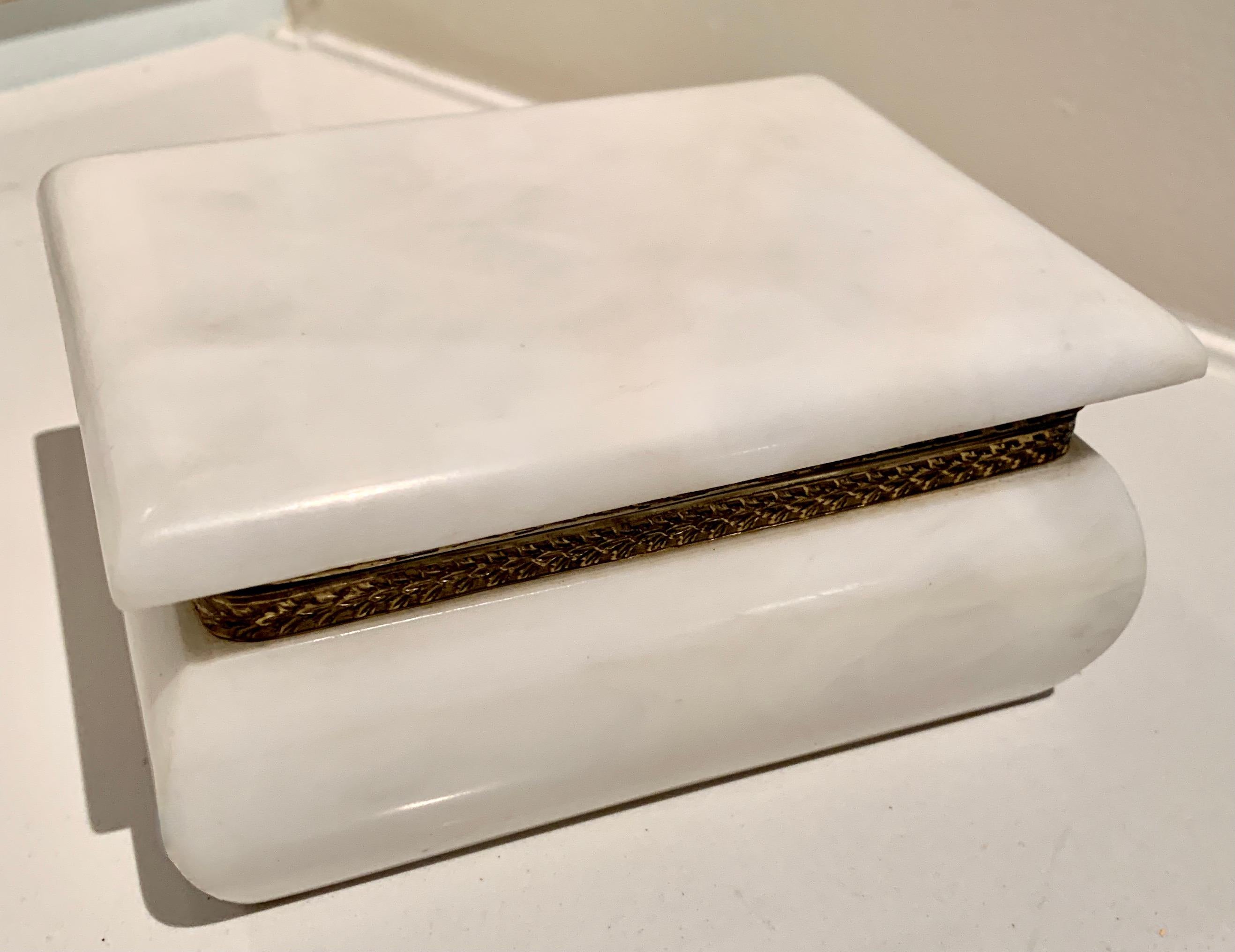 Elegant white Alabaster box with detailed brass hinged surround. A great piece for any vanity or dressing table. The clean look of alabaster compliments any environment, from Ultra Modern to the most traditional. 

A trinket box perfect for those