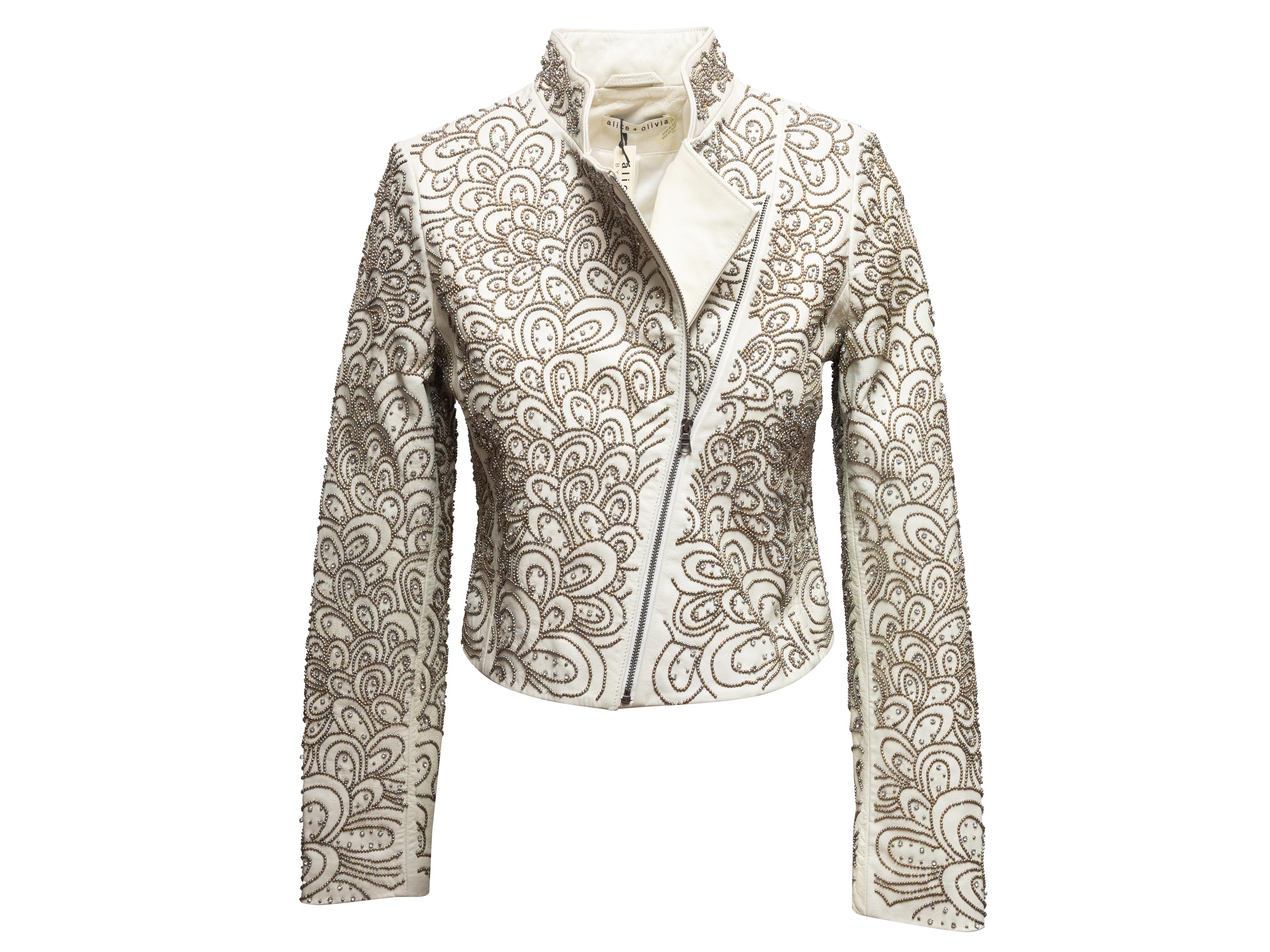 Weiße, mit Leder verzierte Moto-Jacke von Alice + Olivia. Durchgängig mit silberfarbenen Perlenverzierungen versehen. Stehkragen. Asymmetrischer Reißverschluss auf der Vorderseite. 38