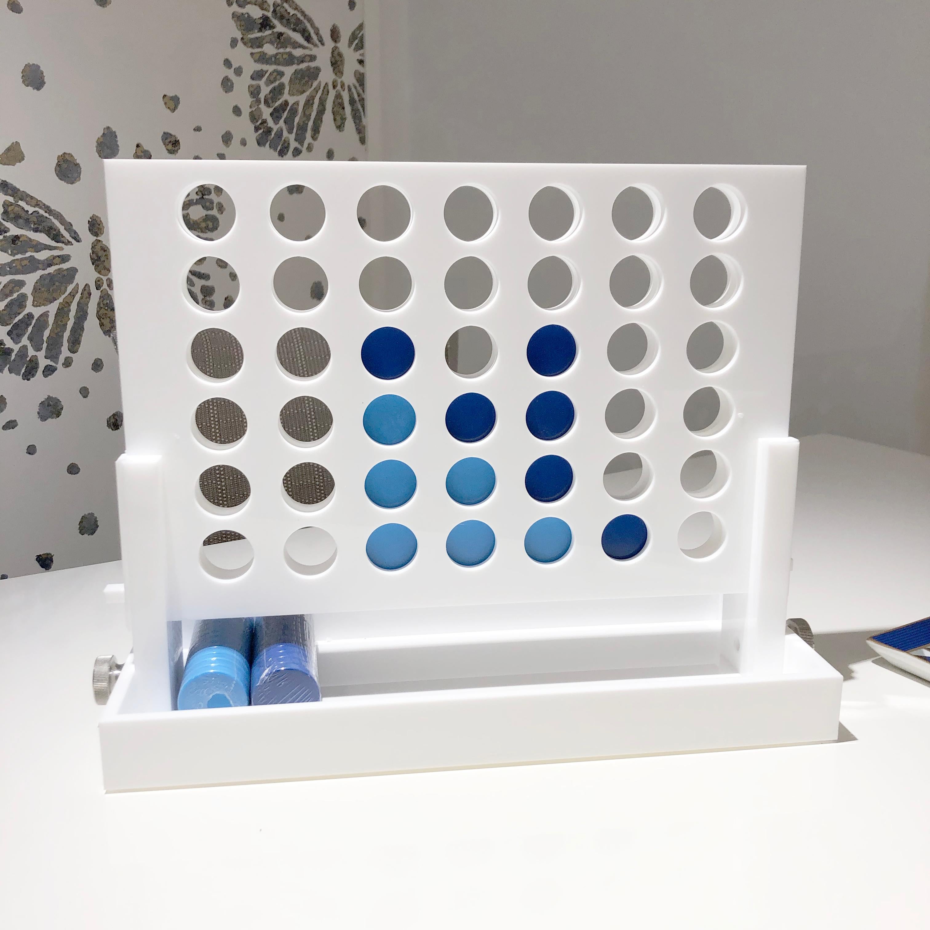 The classic game of Connect Four is reimagined. Crafted out of acrylic and lacquered white, the game features dark and light blue chips that are pleasing to the eye; allowing this piece to be kept out year round as decor. 

Measurements

13” H x