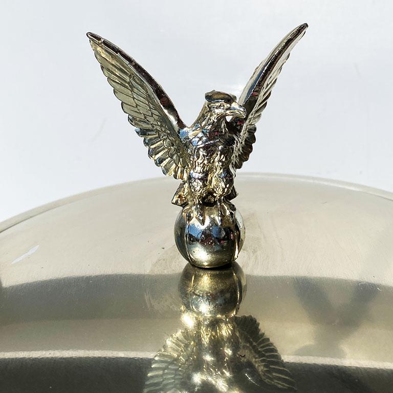 Make a grand statement to a bar with this regal eagle motif ice bucket. The sides are channel-tufted in white vinyl. The base is surrounded by a beautiful brass ring. Brass ring handles are affixed to both sides, and a gold metal lid with an eagle