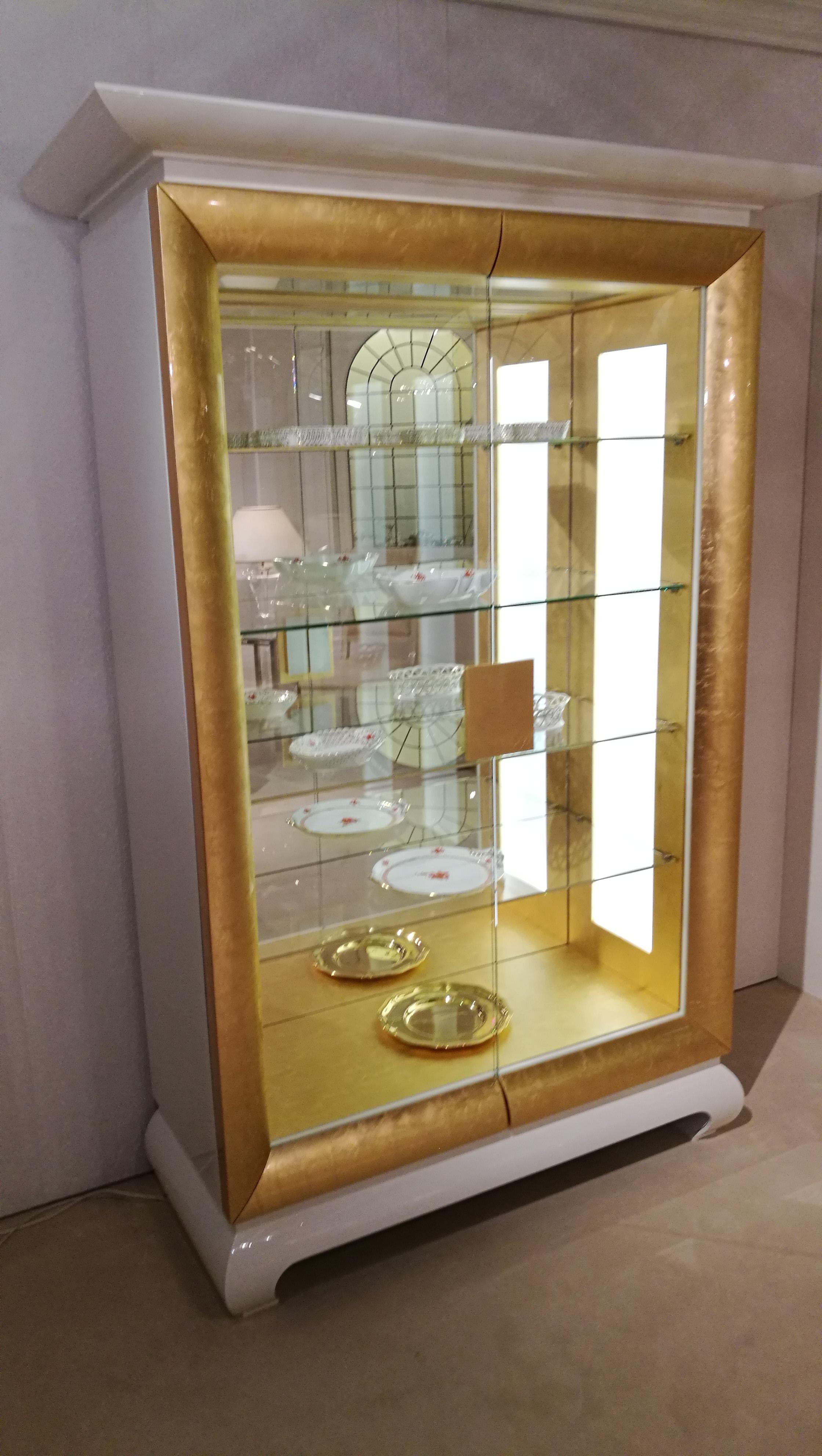 Stunning white and gold design vitrine with glass shelves and smooth interior lighting. The exterior is finished in high gloss white and high gloss gold paintjobs while the interior got lacquered in a beautiful matte gold. On the interior you will