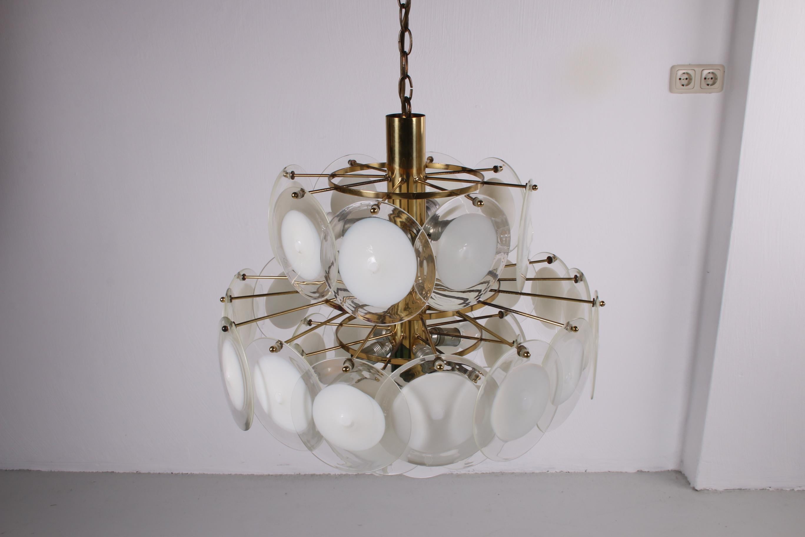 A beautiful lamp by the Italian brand AV Mazzega. It was a populair model in back in it's day and even now this piece still exudes style and class. 

The frame of this chandelier is made of gold coloured chrome. The 36 disks that surround the