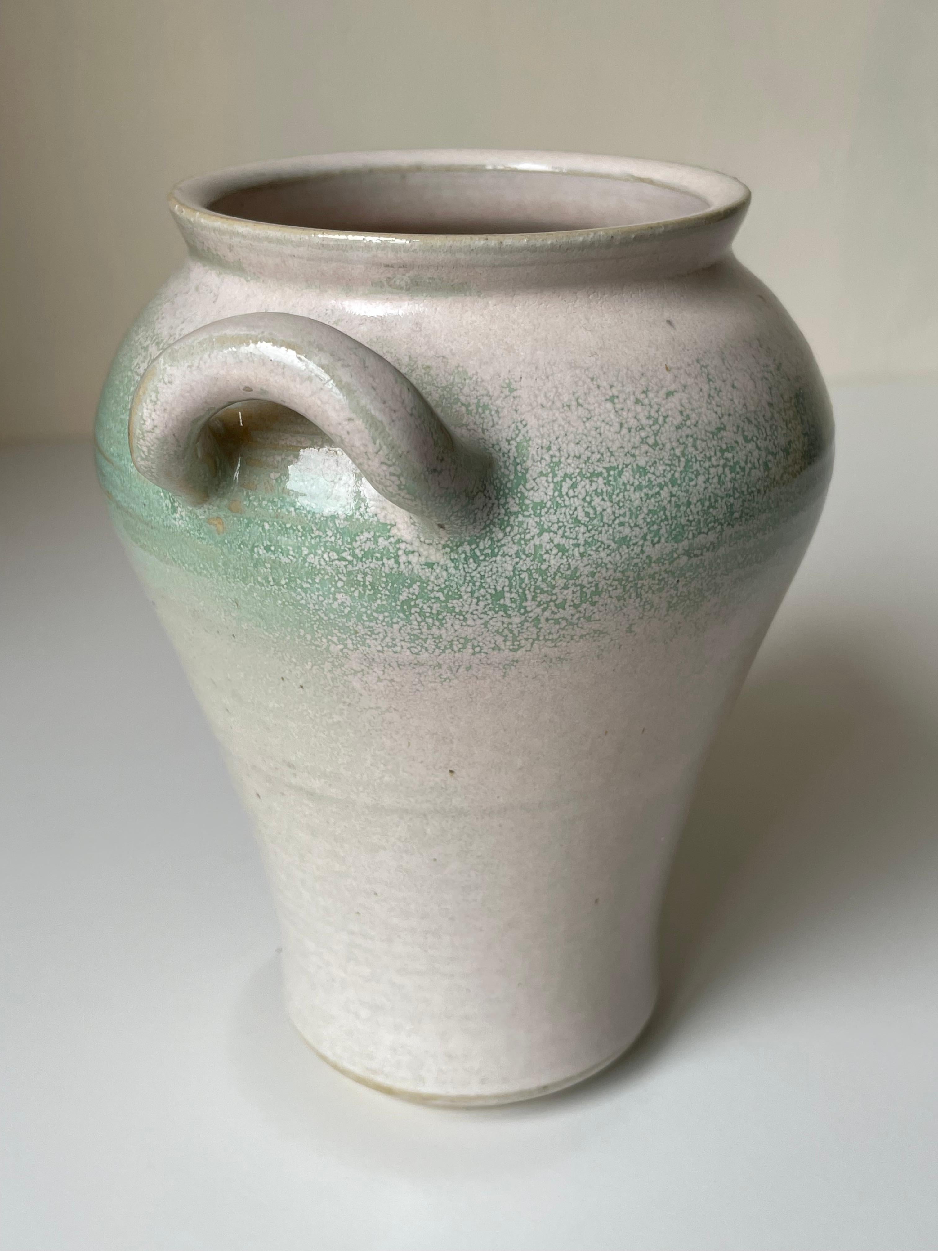 Beautifully glazed Nordic modern warm parchment white and pastel seafoam green amphora stoneware vase manufactured by Skottorp Stengods Hantwerk in Sweden in the 1970s. Two small soft shaped handles on the wide top. Stamped under base. Beautiful