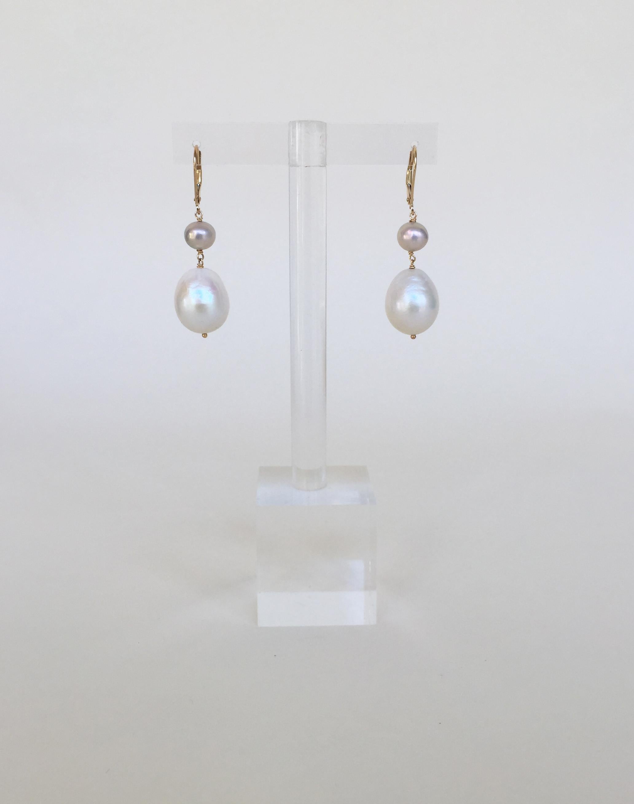 These white and grey pearl drop earrings with 14k yellow gold lever backs glow in the light. The large oval white pearl and small round light pink tinted grey pearl complete each other, for a timeless and elegant look. The 14k yellow gold lever
