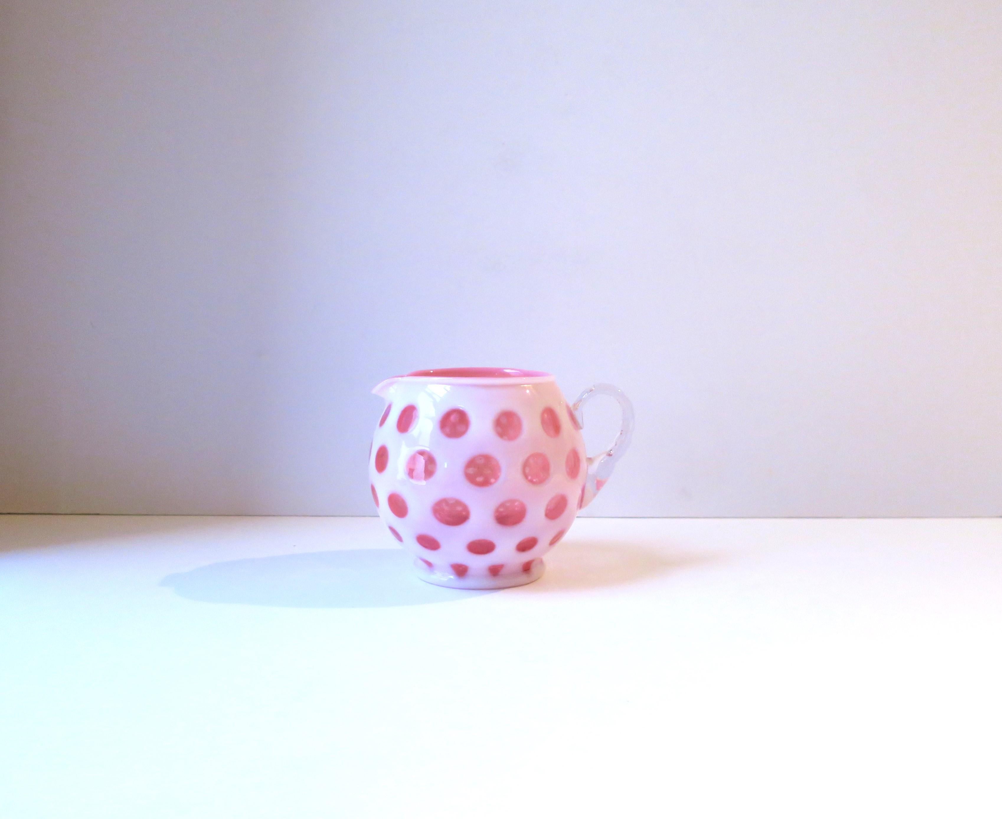 A beautiful vintage pink and white art glass pitcher or vase with polka dot design, circa early to mid-20th century, USA. A beautiful white and pink polka dot art glass pitcher with clear/transparent handle. Great as a standalone piece, on a shelf,