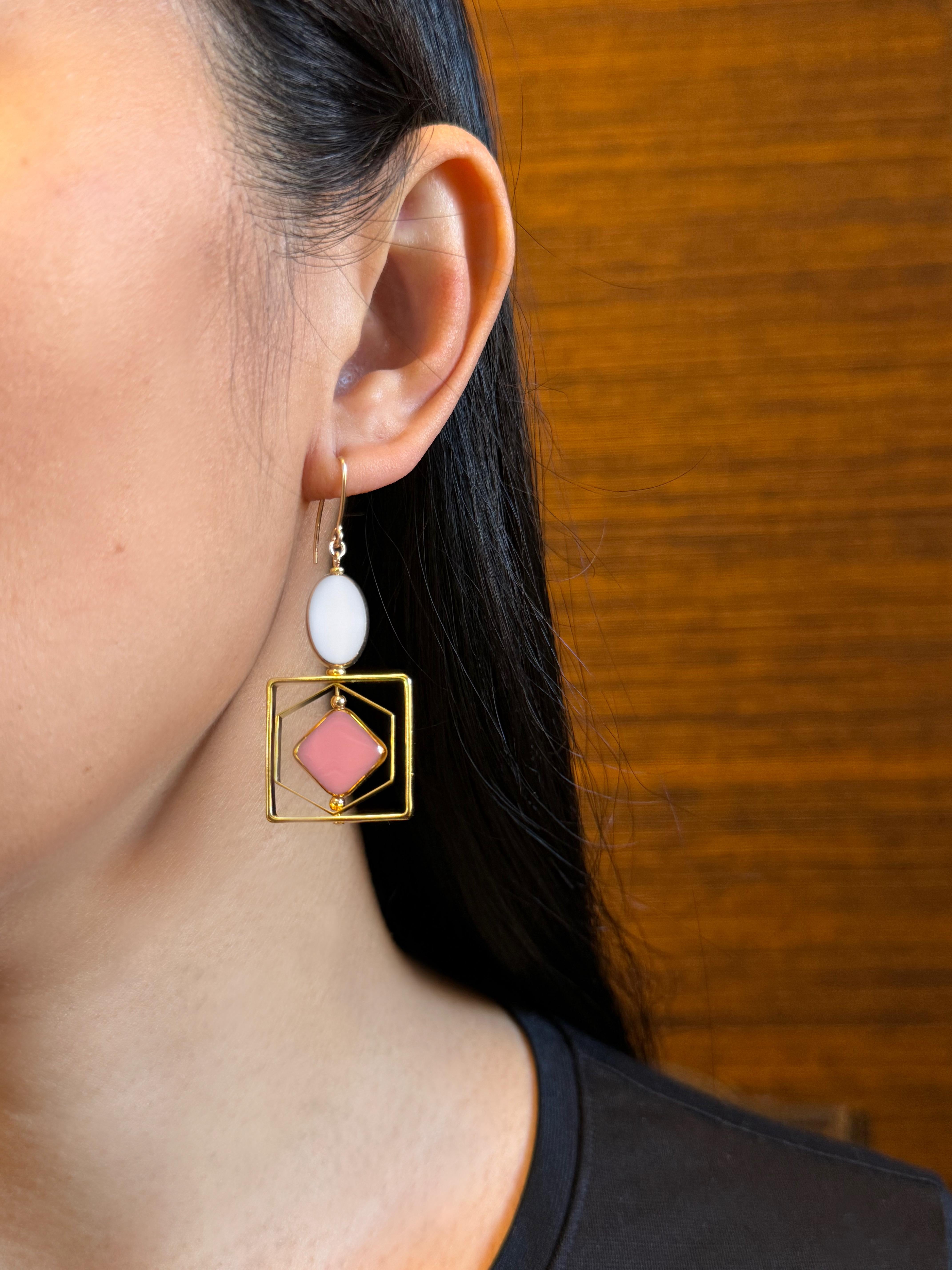The earrings are light weight and are made to rotate and reposition with movement.

The earrings consist of white and pink new old stock vintage German glass beads that are framed with 24K gold. The beads were hand pressed during the 1920s-1960s in