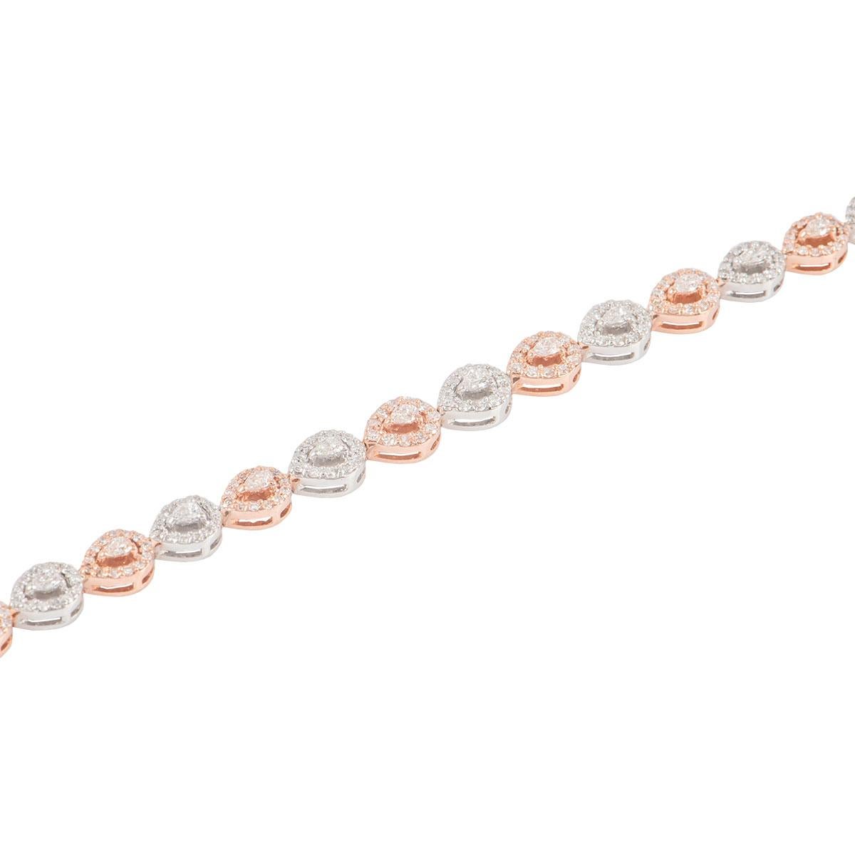 An 18k white and rose gold diamond line bracelet. The bracelet is made up of 24 pear cut diamonds each complemented by a halo of round brilliant cut diamonds around the outer edge. The pear cut diamonds have a total weight of 1.03ct and the round