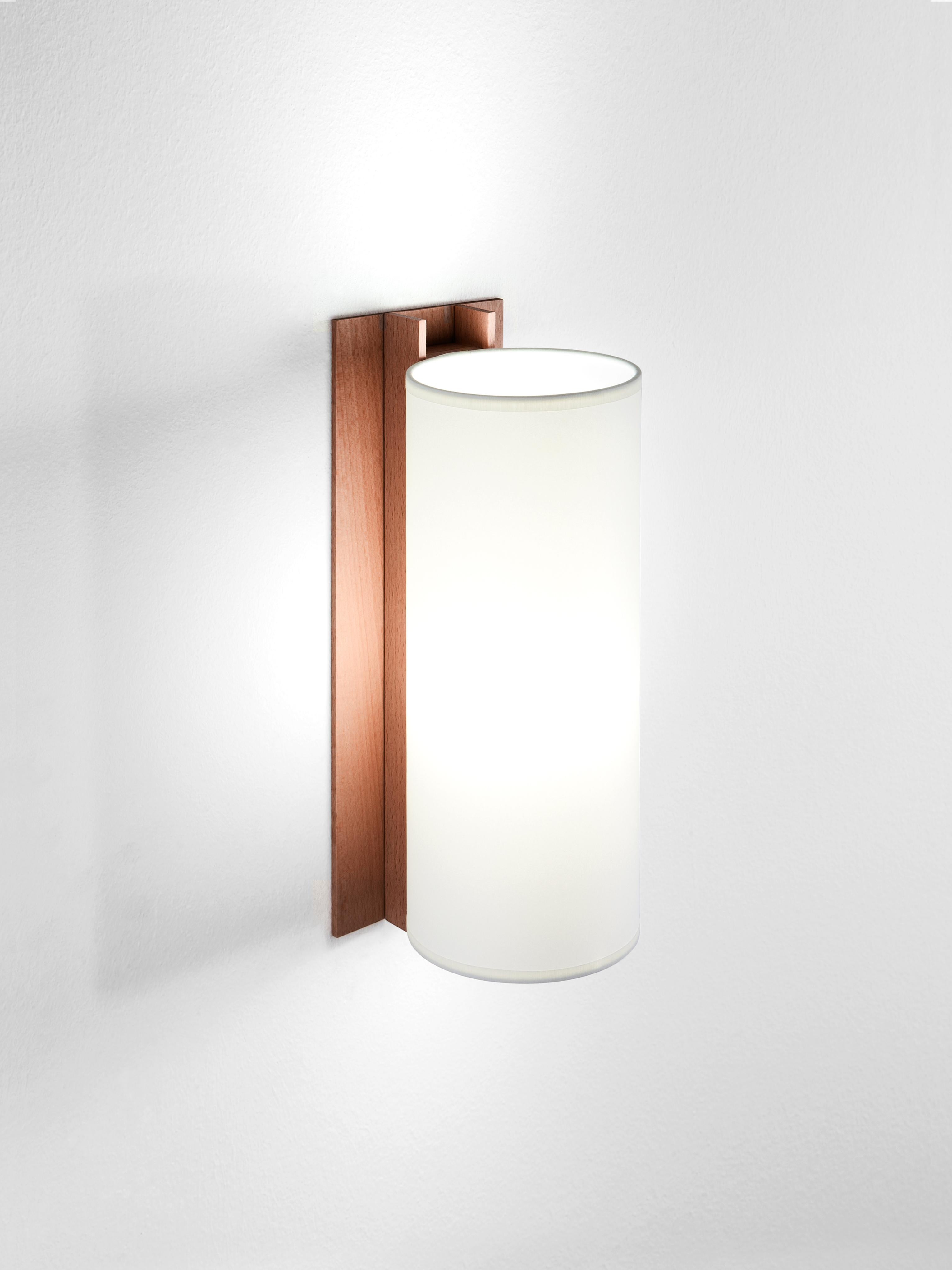 White and walnut TMM largo wall lamp by Miguel Milá
Dimensions: D 12 x W 15 x H 34 cm
Materials: Metal, walnut wood, parchment lampshade.
Available in beech or walnut and in white or beige lampshade.

The long and short wall lamps belonging to the