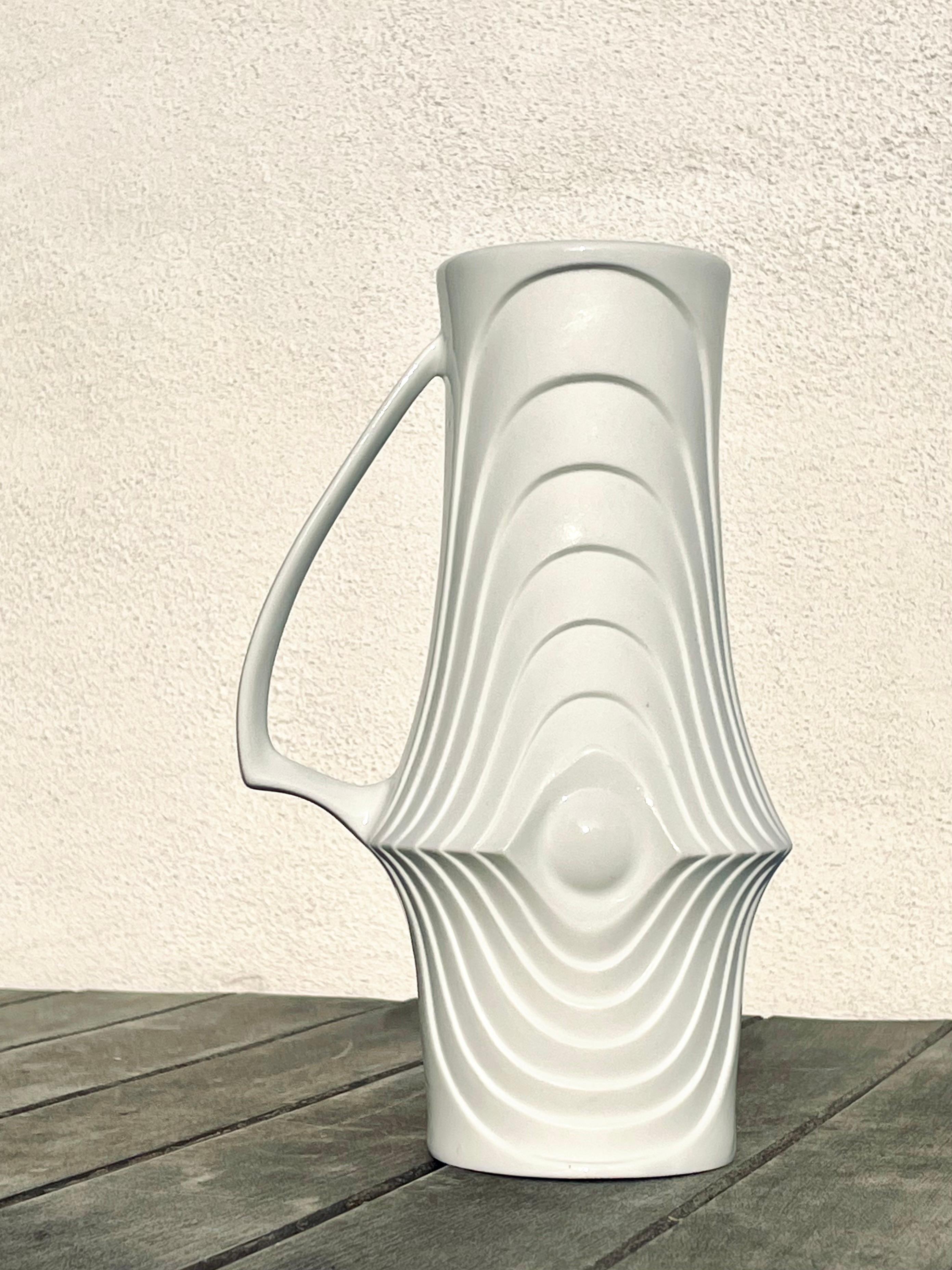 Handmade Modern Op Art bone white modernist textured handle vase of high quality bisque porcelain. Sculptural Art Deco angled shape with low placed slender triangular handle on one side. The interior has been given a clear glossy glaze, and the same