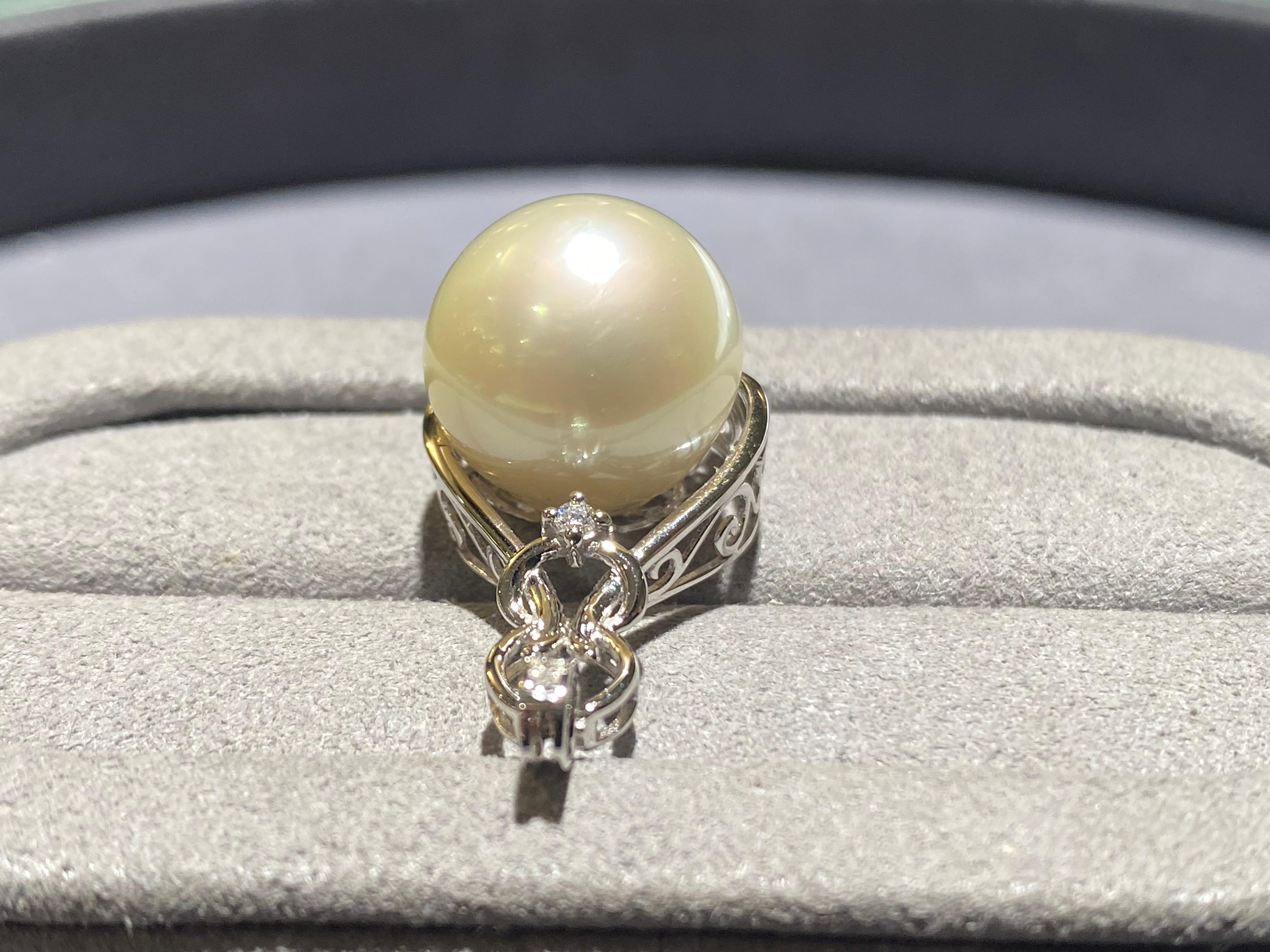 A round 13.5 mm white australian south sea pearl and diamond pendant in 18k white gold. The pearl is set at the bottom of the rain drop and there is a diamond set directly above the pearl. The bale is also set with diamond pave. The pearl is white