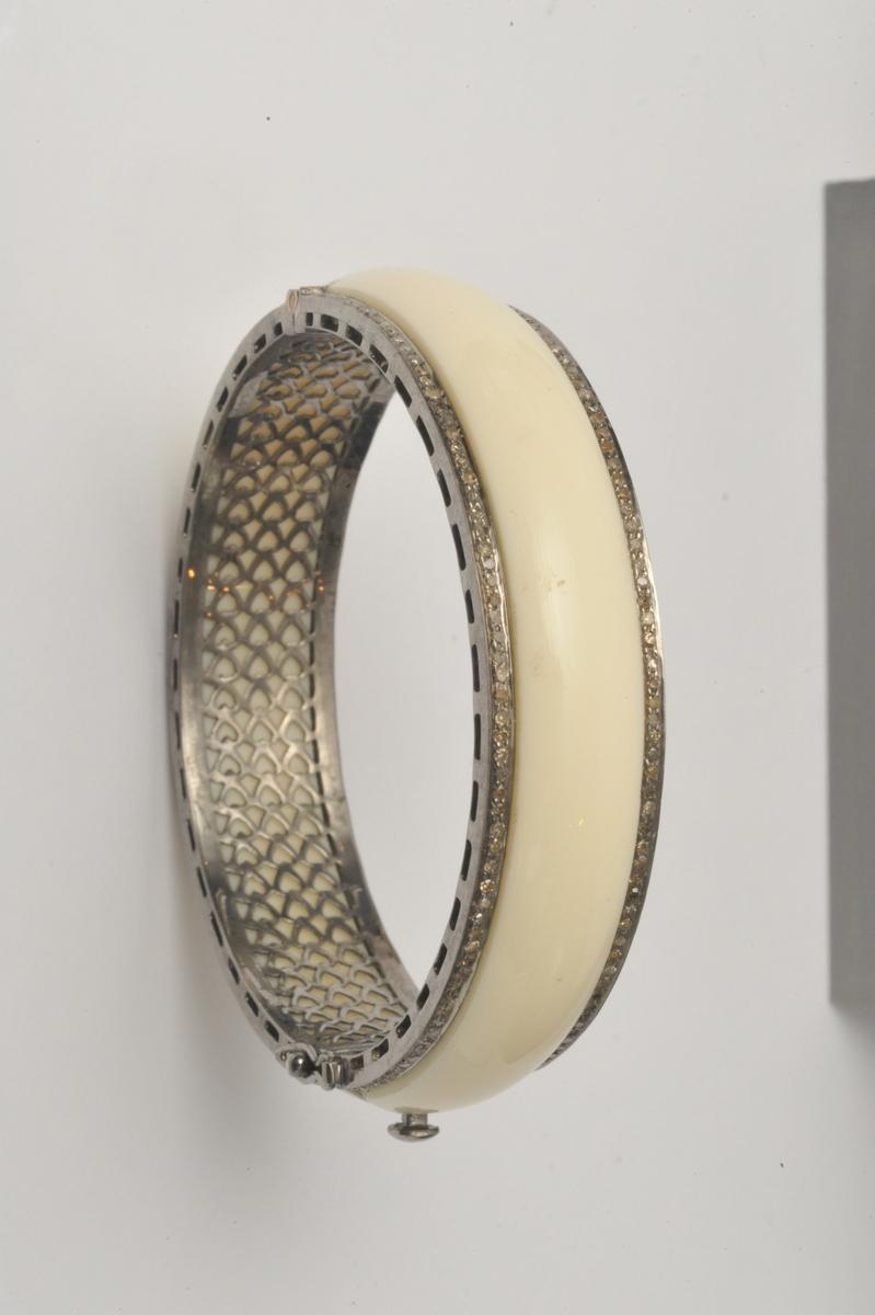 Lovely white bakelite bangle bordered in pave` set diamonds.  Sterling silver interior and sides.  Push clasp with safeties.  Great piece to wear with others or on its own.  Inside circumference is 7 inches.  Carat weight of diamonds is 2.64