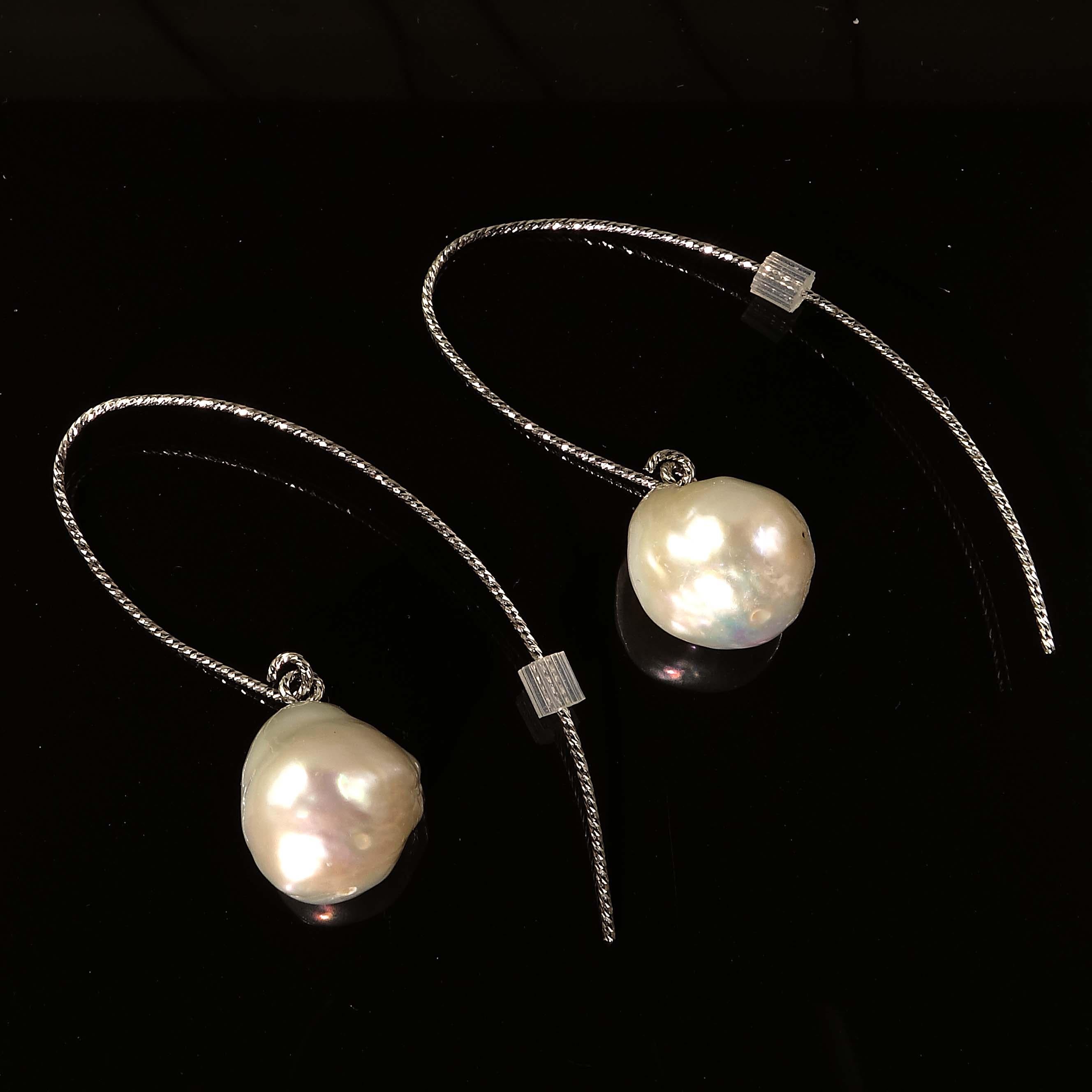 Custom made earrings of Iridescent White Baroque Pearls Dangling from twisted Sterling Silver Hooks.  The twisted wire sparkles and enhances the pearls. The Pearls are off Round and flash lovely shades of pink and yellow.  The Sterling Silver wires