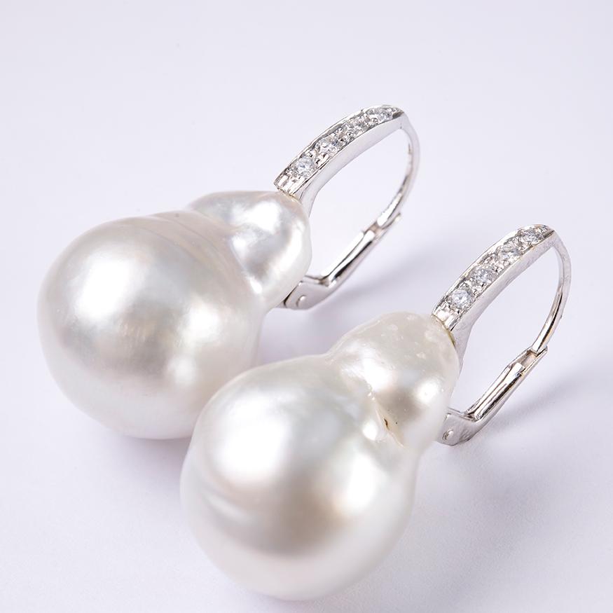 A Pair of Baroque Cultured South Sea Pearls measuring 24.14 - 18.4mm and 22.00 - 17.18mm each, of White Color with Silver Overtones, set in 18 Karat White Gold and Diamonds, Total Weight 0.24 Carat, H color, VS1 Clarity. Earrings for Pierced Ears.