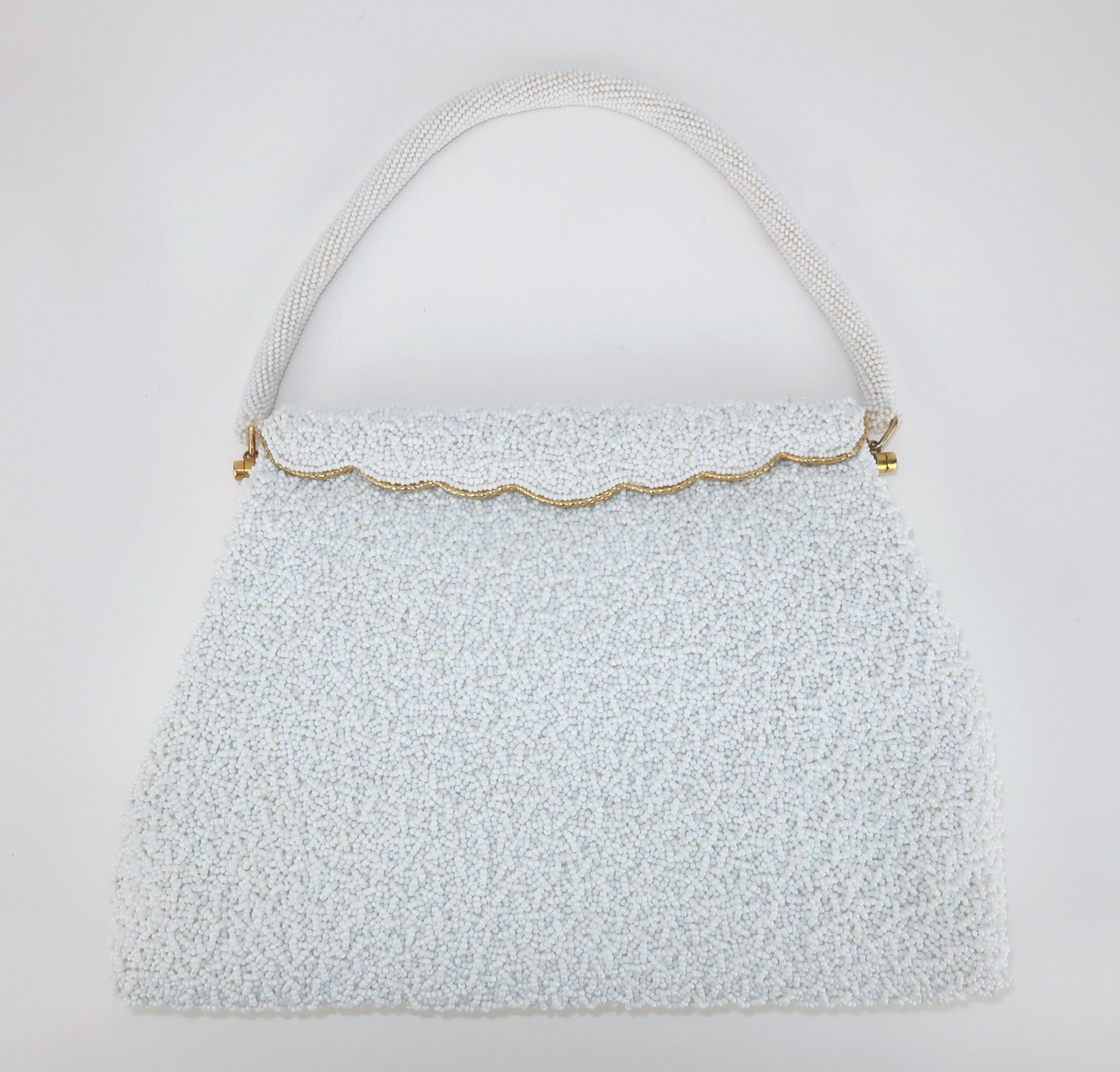 Lovely 1950’s white beaded handbag with a gilt gold metal frame. The beading on this bag is spectacular with every inch covered including the top handle.  The gilt gold frame is scalloped at the spring loaded front closure which opens to reveal a