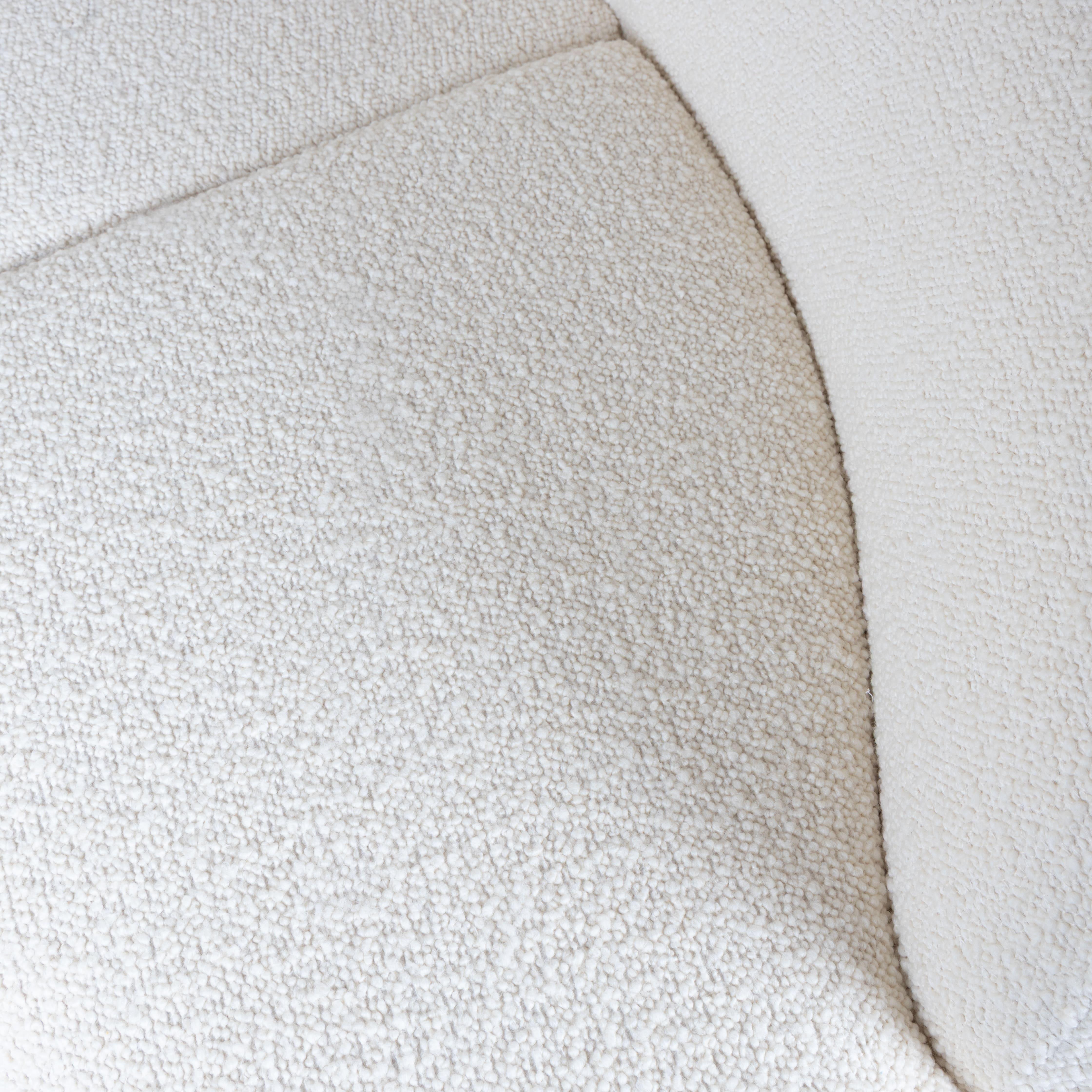 “Fagiolone” model sofa with white bouclé fabric upholstery, probably made in Italy around the 1960s. The soft and enveloping shape, characterized by full volumes and continuous profiles, reflects the search for organic design of the period, oriented