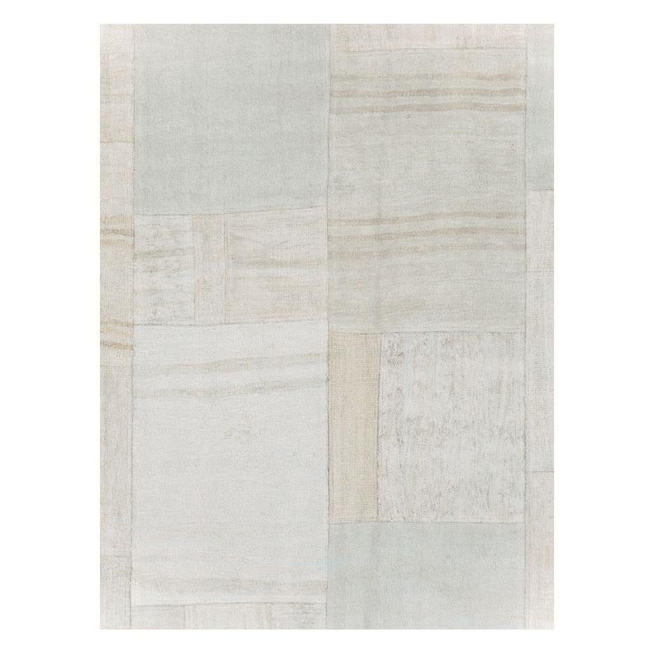 A contemporary Turkish flatweave Kilim room size carpet handmade during the 21st century in shades of white and beige. This patchwork style rug consists of hand-weaving together several remnants of vintage Kilim carpets from the mid-20th century