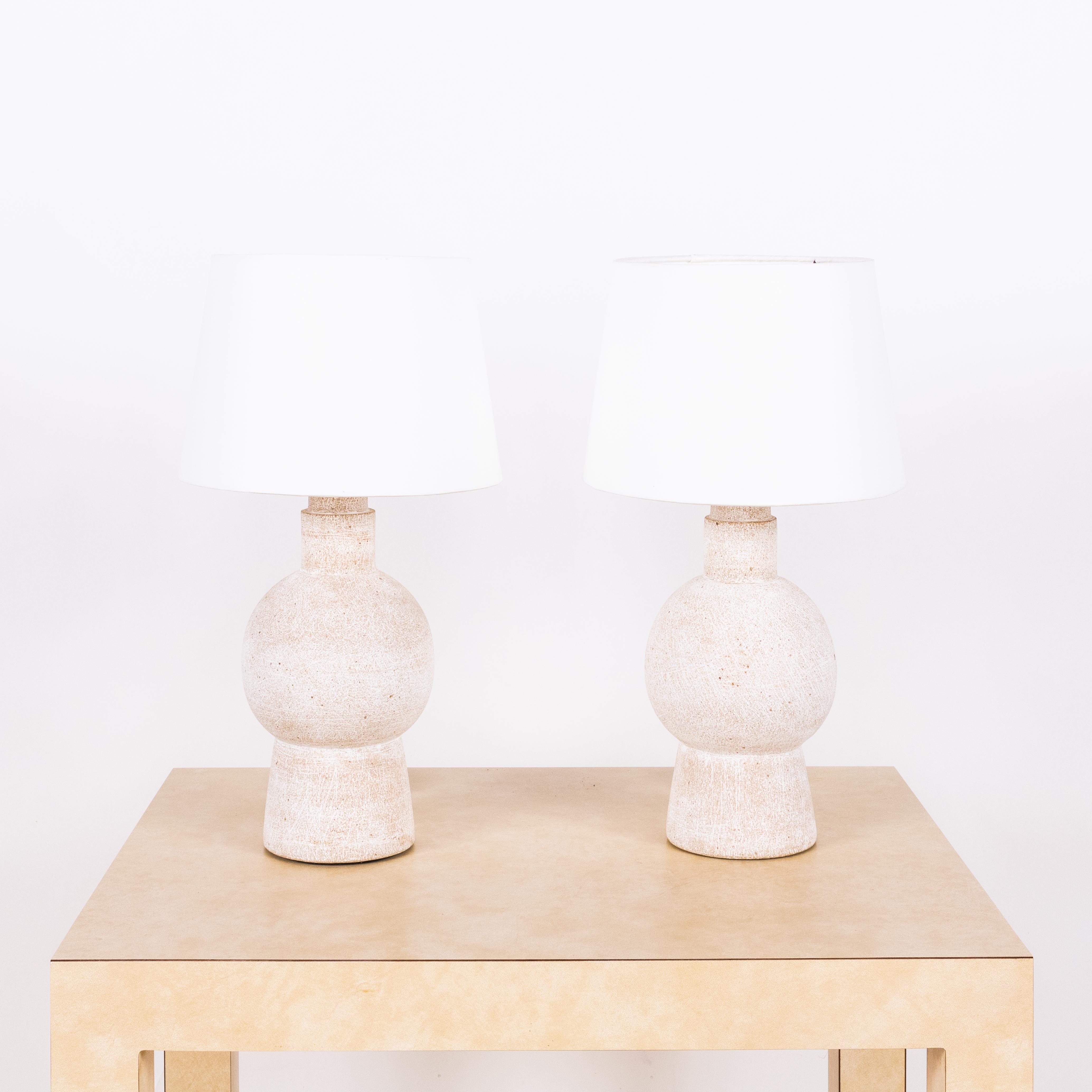 Pair of white 'Bilboquet' stoneware lamps by Design Frères.

Dimensions listed (10 in. diameter x 18 in. tall) are the overall dimensions of the lamps plus the shades (as pictured). The lamp bases are 11 in. tall and the shades are 7 in. tall.