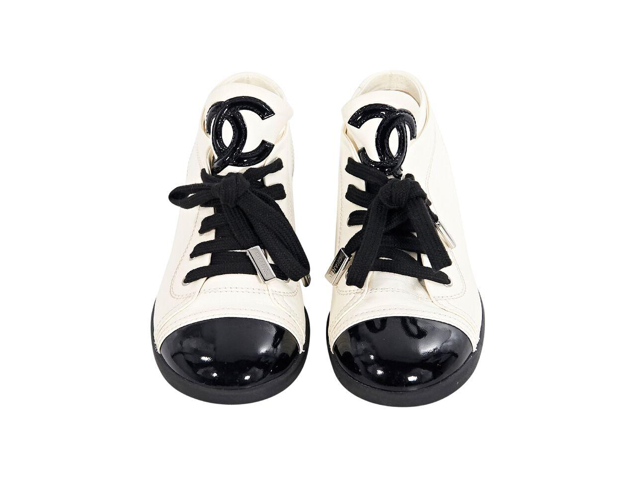 Product details:  White leather sneakers by Chanel.  Accented with black patent leather.  Logo detail on tongue.  Lace-up closure.  Round cap toe.  
Condition: Pre-owned. Very good.
Est. Retail $ 1,100.00