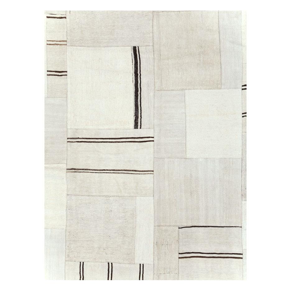 A contemporary Turkish flatweave Kilim large room size carpet handmade during the 21st century in shades of white and black. This patchwork style rug consists of hand-weaving together several remnants of vintage Kilim carpets from the mid-20th