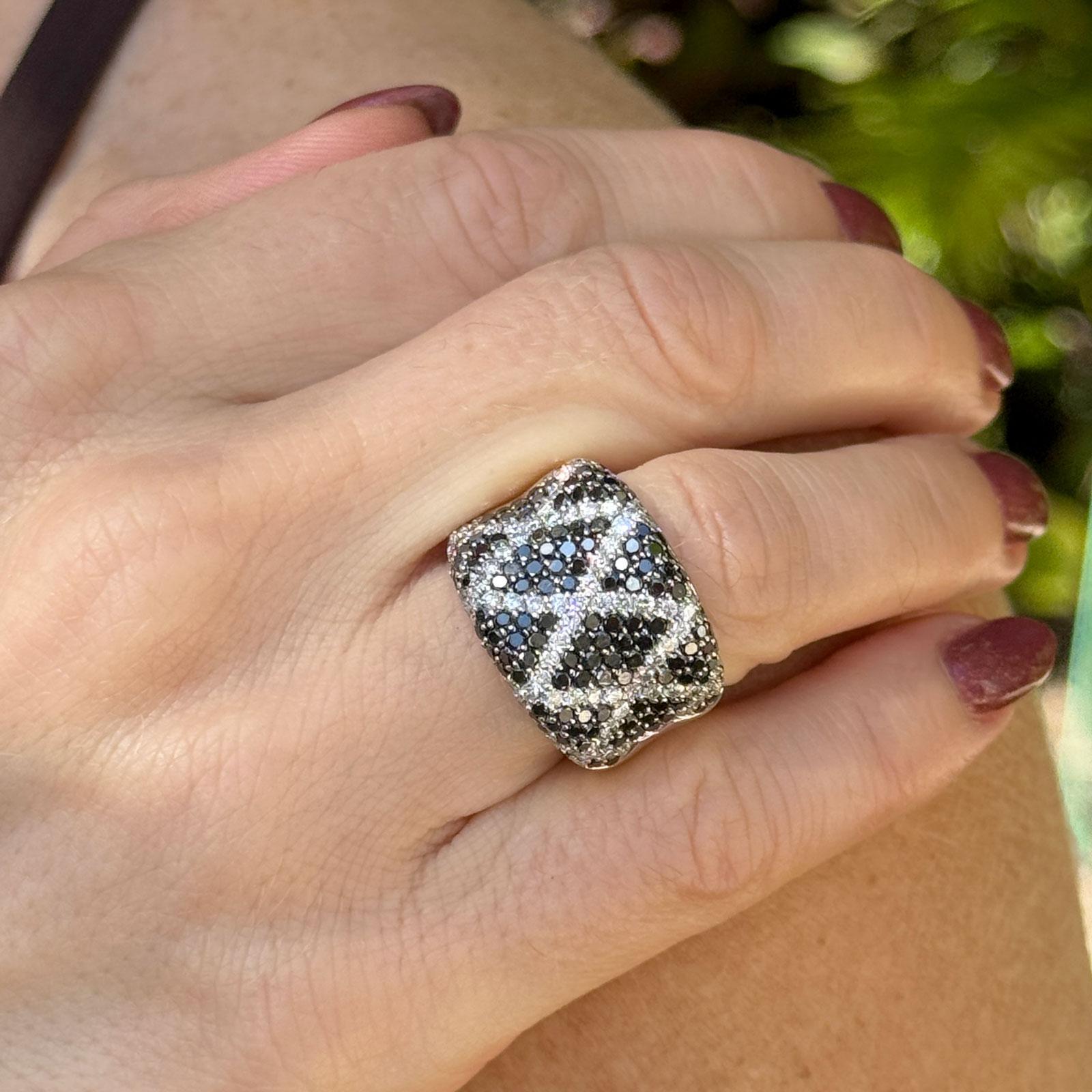 This bold 14k white gold ring showcases a striking X-pattern of brilliant white and black diamonds, featuring 83 white round brilliant-cut stones totaling approximately 1.25 carats in I-J color and SI clarity, intertwined with 132 round black