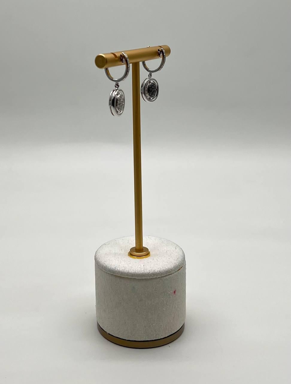 Ces boucles d'oreilles exquises présentent un design moderne et élégant avec une finition polie. Les boucles d'oreilles sont ornées de médaillons complexes qui ajoutent une touche de sophistication. Fabriquées avec précision, elles sont suspendues