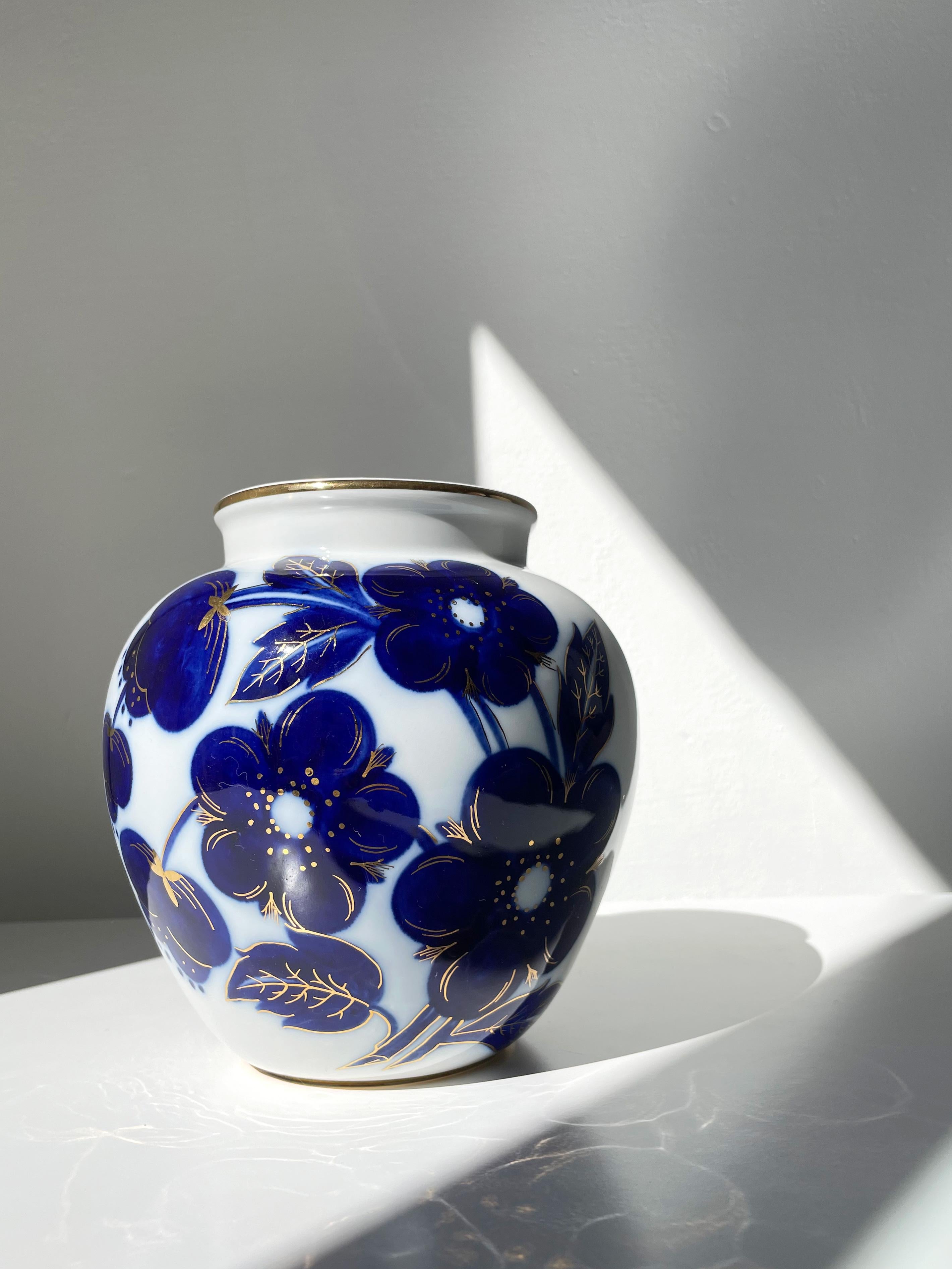 Russian white porcelain vase manufactured in the 1950s by the Lomonosov Porcelain Factory (founded in 1744). Soft shaped organic Mid-Century Modern vase decorated by hand with large mineral cobalt blue flowers, stems, leaves and 22K gold accents.
