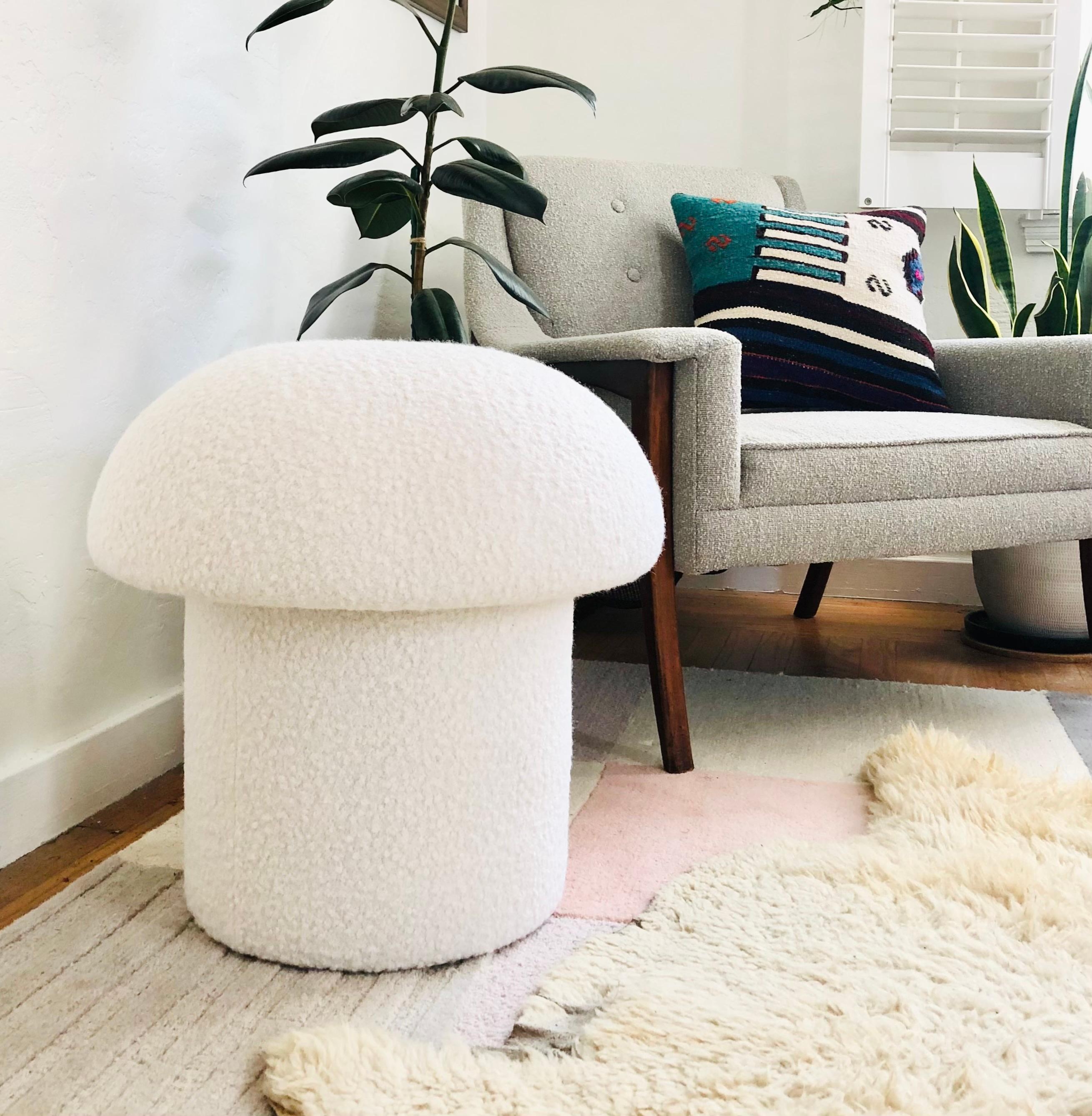 A handmade mushroom shaped stool, upholstered in a white colored curly boucle fabric. Perfect for using as a footstool or extra occasional seating. A comfortable cushioned seat and sculptural accent piece.