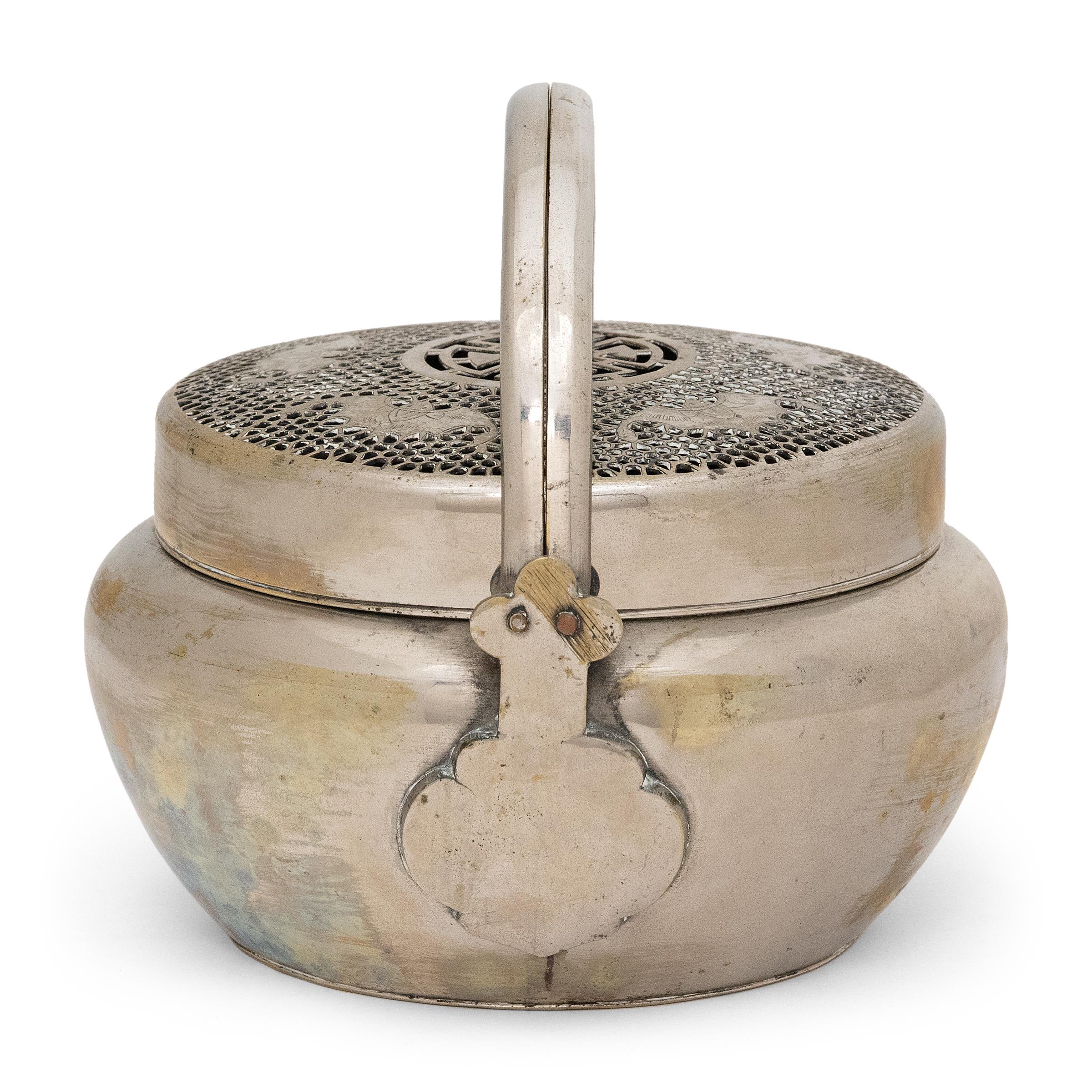 Filled with burning coals, this finely crafted 19th-century brazier once warmed the hands of a wealthy lady on a cold winter's night in northern China. The portable brazier is hand-wrought of white brass with a rounded body, two arched handles and