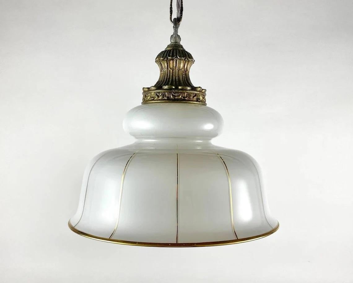 Cast brass frame of bronze color and opaline glass white lampshade with gilt decor and rim perfectly complement the interior of the kitchen, corridor or in any other room that can do with a stylish upgrade.

Midcentury brass light fixture comes with