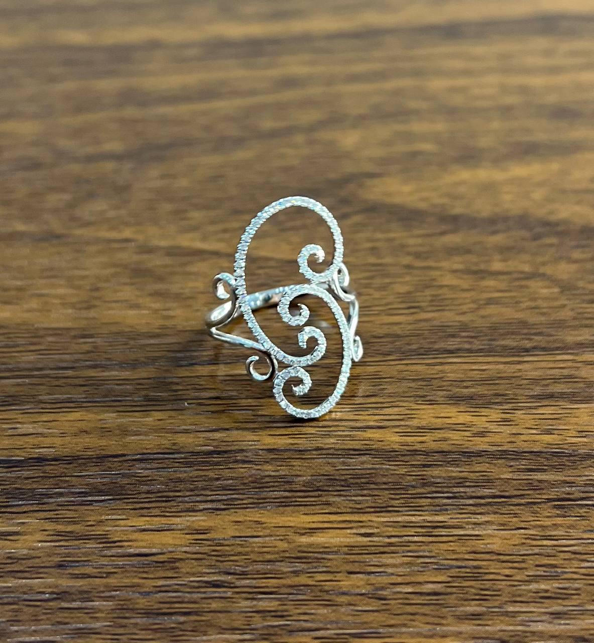 Questo pezzo accattivante presenta un delicato design traforato, che mostra intricati motivi vorticosi che danzano con grazia sulle dita.

La struttura ariosa dell'anello è ornata da scintillanti diamanti incastonati a pavé, che creano un ipnotico