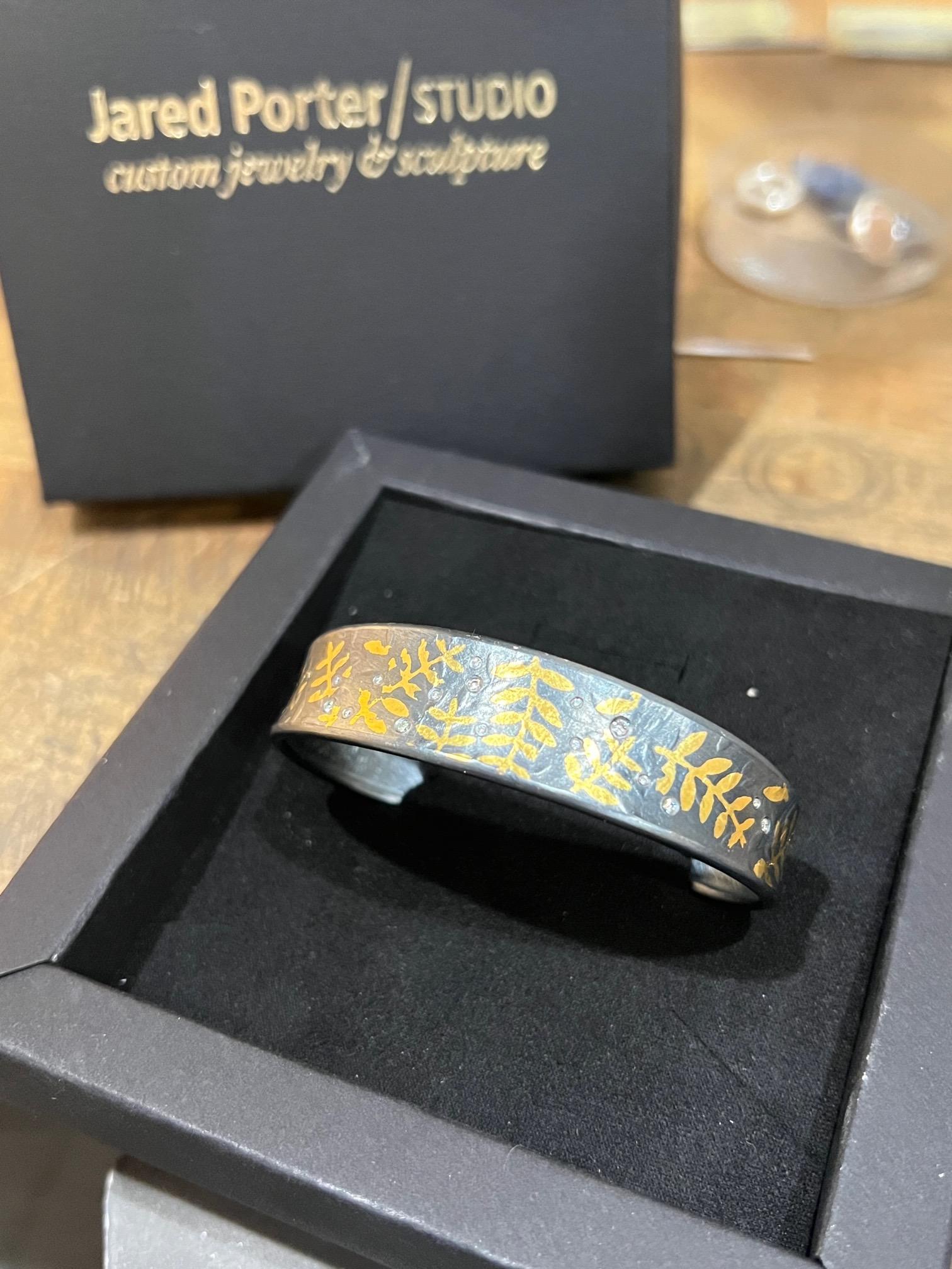 White Brilliant Cut Diamond And 24K Keum-boo Gold Leaf Fern Cuff Bracelet.

Hand forged one-of-a-kind by Jared Porter Studio out of Beautiful Colorado.

Sterling Silver with a Patina (oxidized) finish.

Keum-boo (also Geumbu, Kum-Boo or