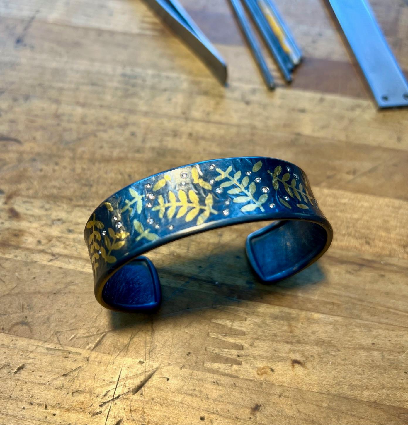 Bracciale con diamanti Whiting e foglie d'oro Keum-boo 24K.

Un pezzo unico forgiato a mano dallo Studio A di Jared Porter in Colorado.

Argento Sterling con finitura Patina (ossidata).

Nota: ogni bracciale è un pezzo unico e la disposizione dei