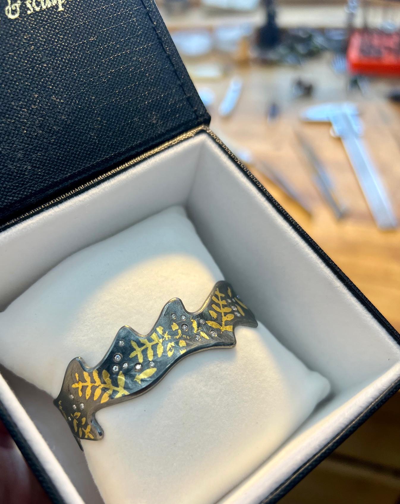 Bracciale a foglia dentellata con diamante Whiting e oro Keum-boo 24K.

Un pezzo unico forgiato a mano dallo Studio A di Jared Porter in Colorado.

Argento Sterling con finitura Patina (ossidata).

Nota: ogni bracciale è un pezzo unico e la