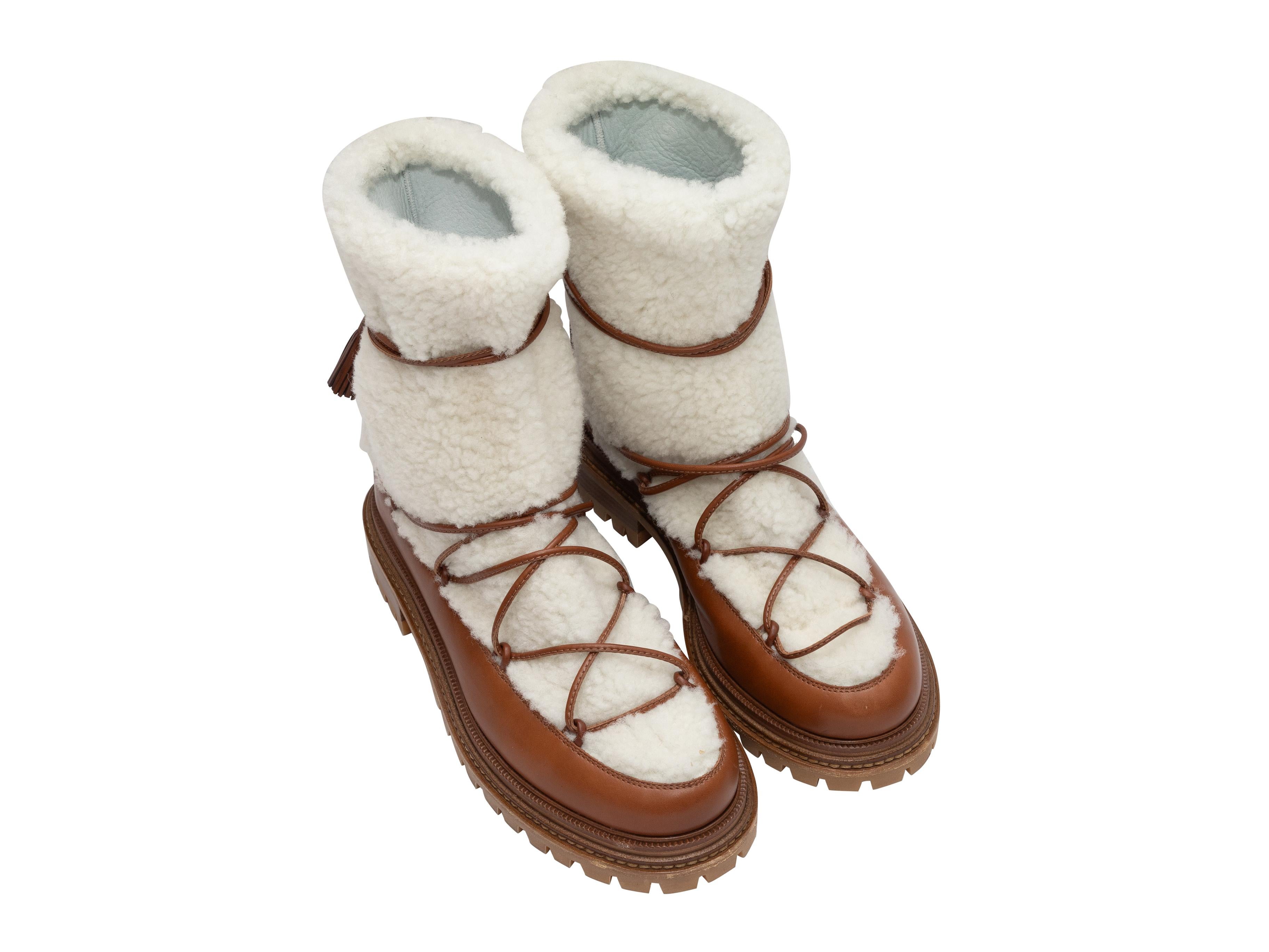 White shearling and brown leather snow boots by Aquazzura. Lug soles. Lace-up closures at tops. 1.5