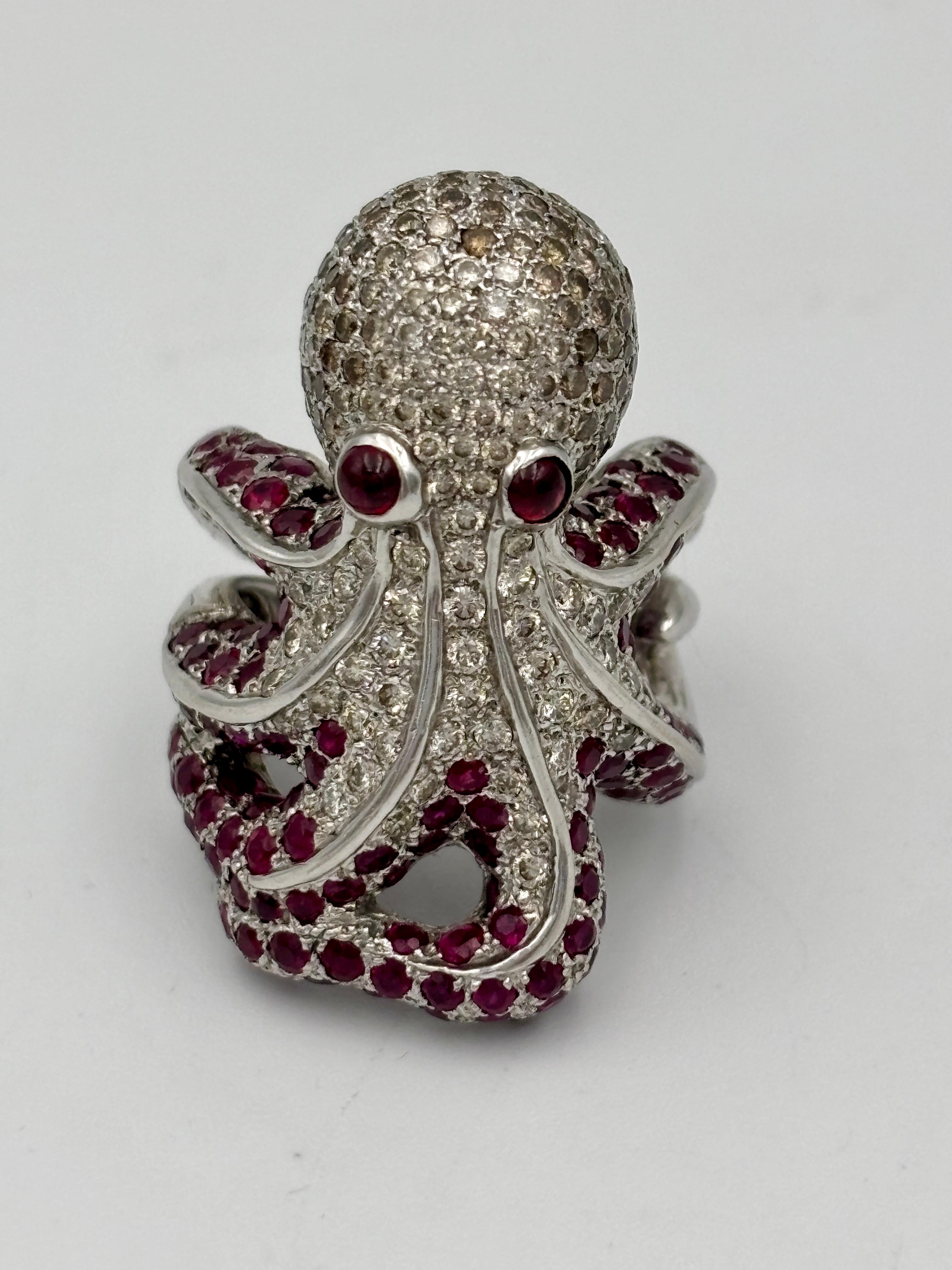 This dramatic 18k white gold octopus ring is adorned with approximately 2 carats of round cut white and brown diamonds. Its eyes and tentacles are accentuated with rubies. It is a striking piece with the octopus wrapping itself completely around the