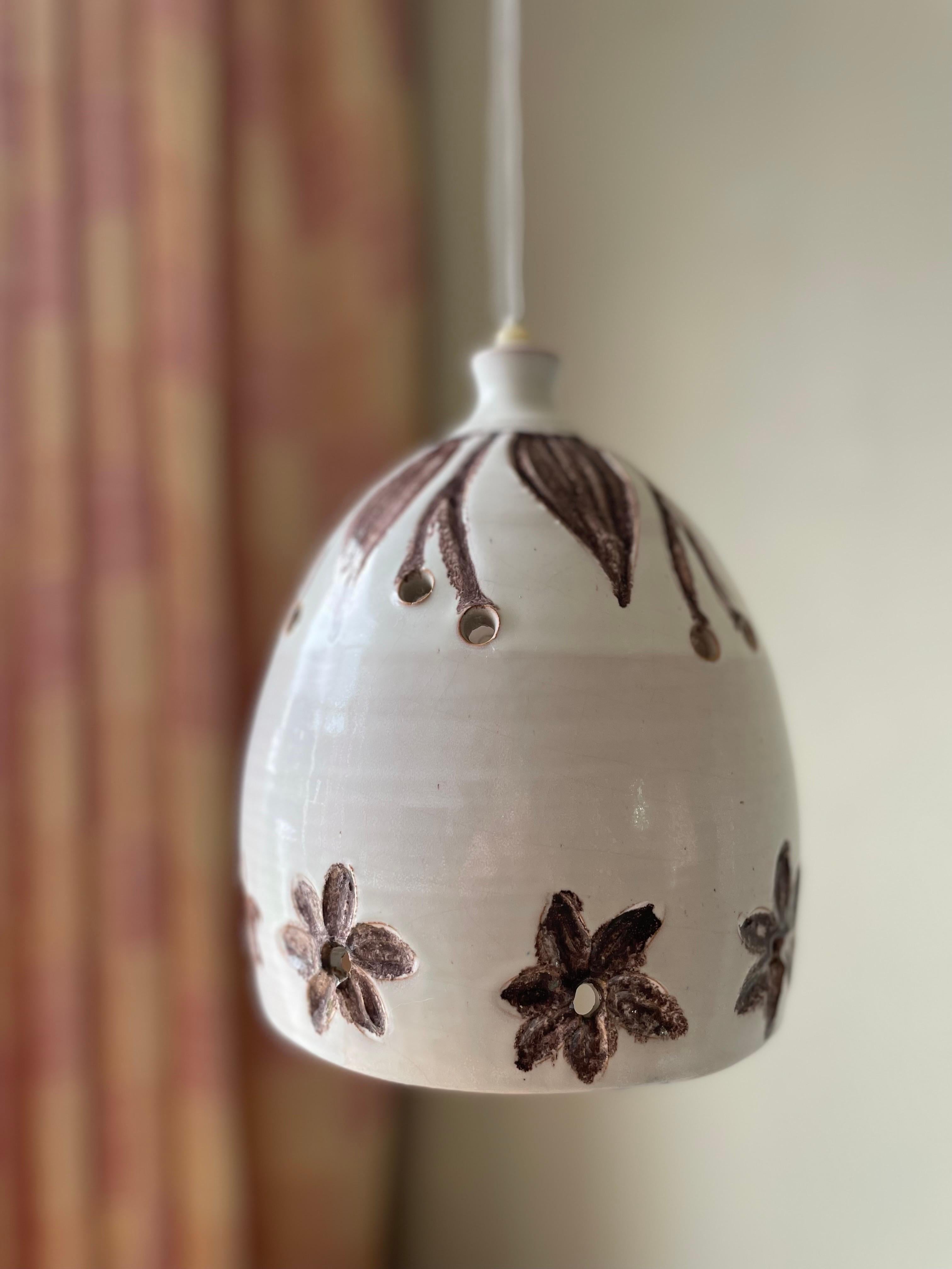 Shiny white glazed handmade organic midcentury modern pendant with hand-carved and hand-painted brown floral relief decor. Circular perforations along the top and bottom to let the light out. Shiny white glaze on the inside, raw bottom edge.