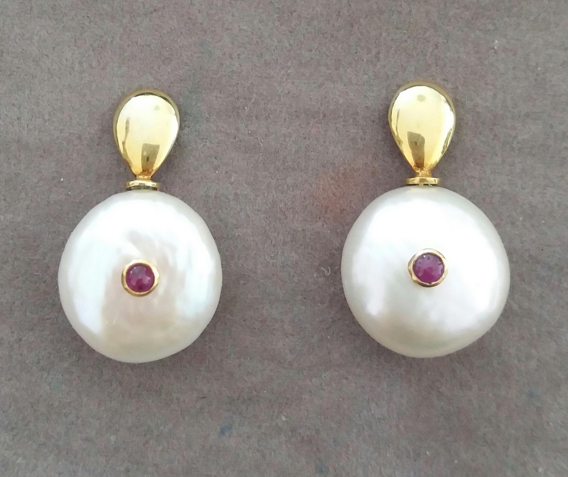  Simple and elegant earrings consisting in 2  Button Shape white color and high luster Baroque Pearls measuring about 17 mm in diameter with in the center 2 small round Ruby cabs set in 14 kt yellow gold suspended from 2 plain yellow gold elements
