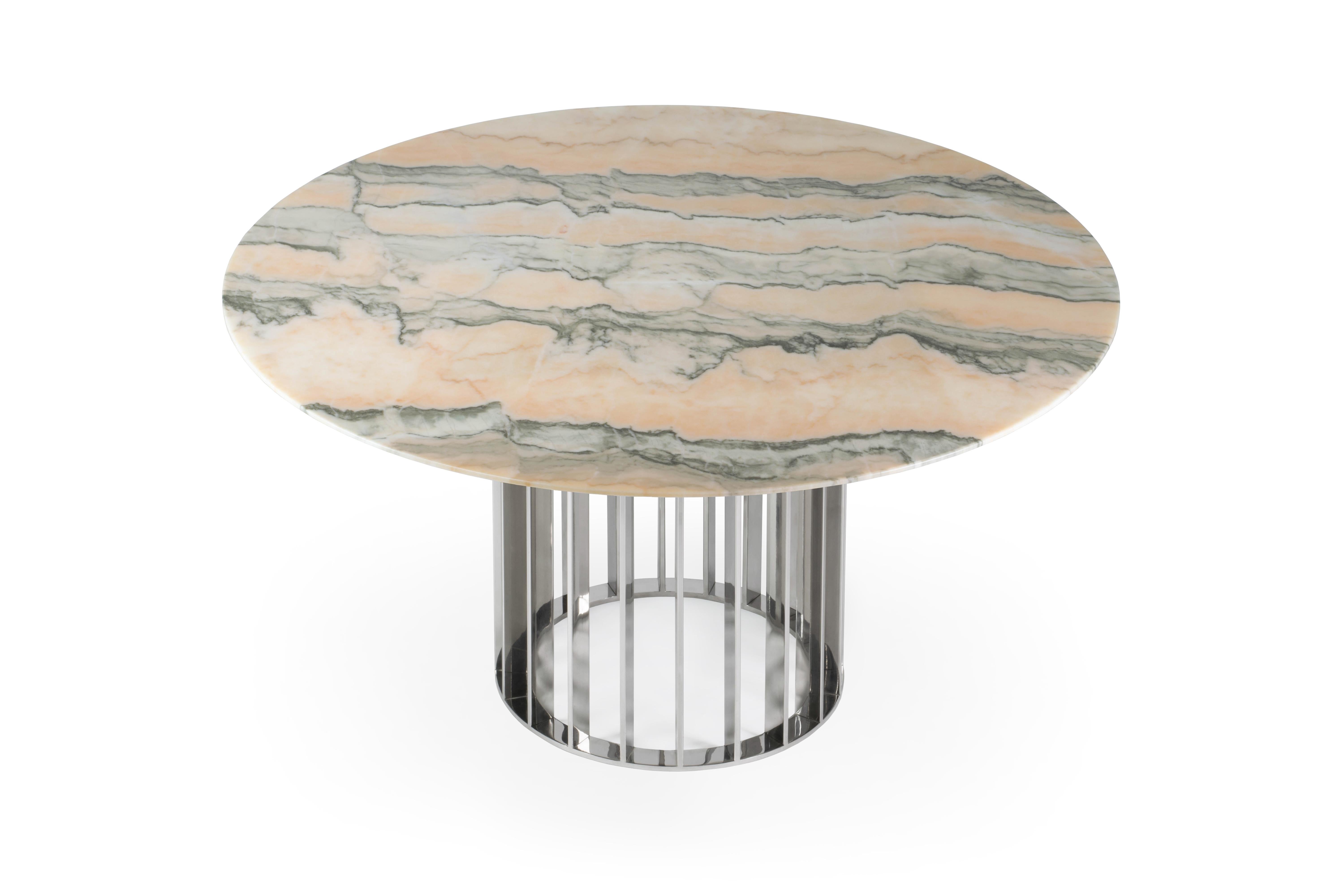 Cette table de salle à manger unique utilise un magnifique plateau en marbre blanc de Carrare à finition mate et une base élégante et moderne en acier inoxydable. La répétition des rayures métalliques donne du rythme à la base. Son design est