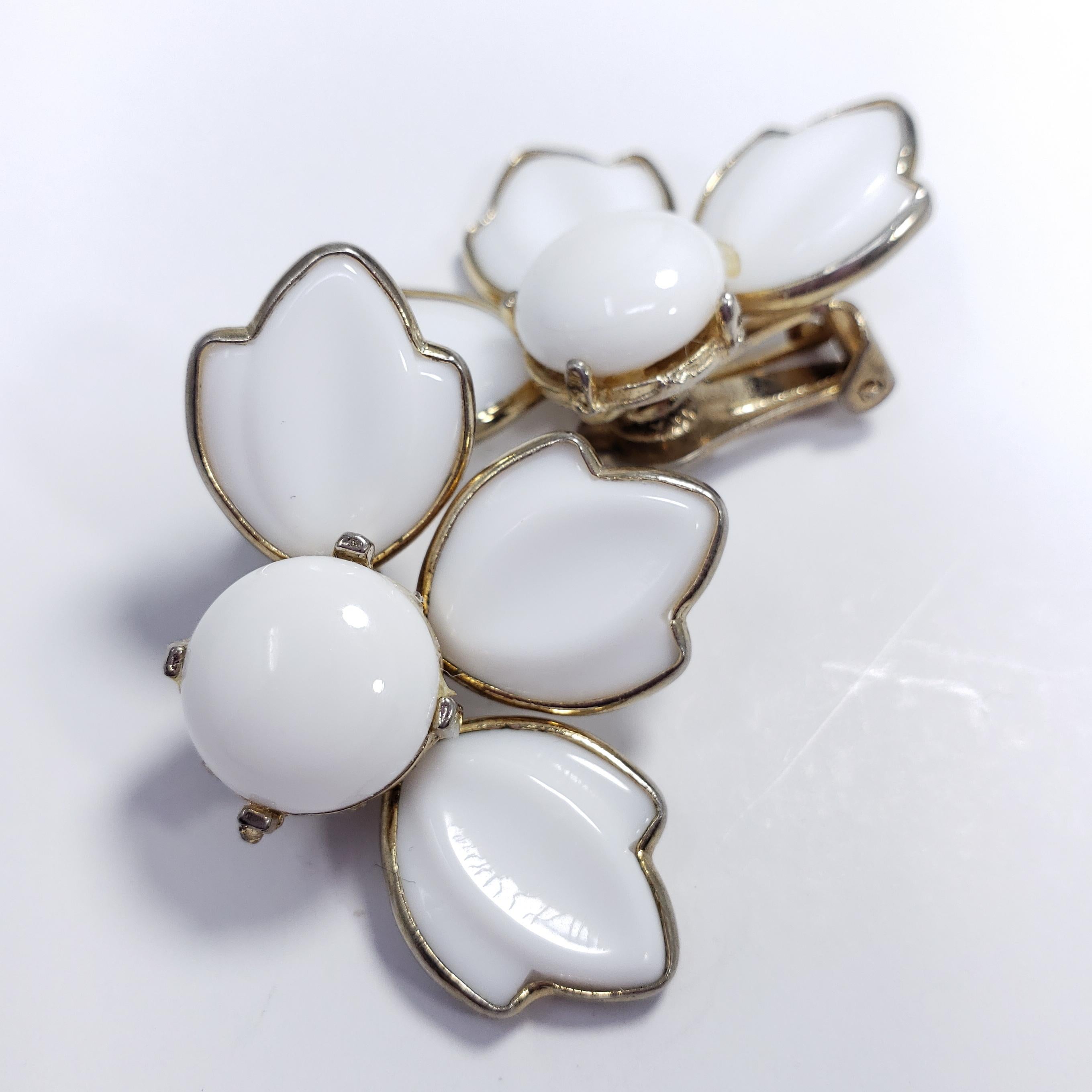 A pair of clip-on earrings featuring white glass petals, set in vintage goldtone metal. Sure to catch attention!