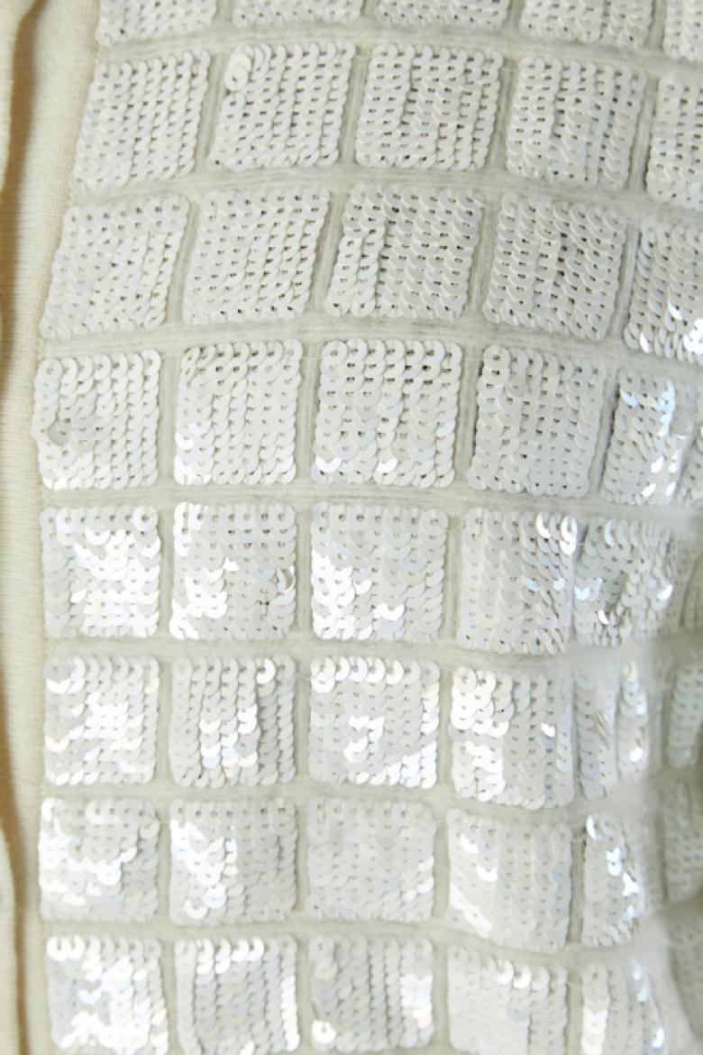 Cardigan en cachemire blanc avec fermeture à paillettes et bouton de marque sur le milieu du devant. 
TAILLE M/L