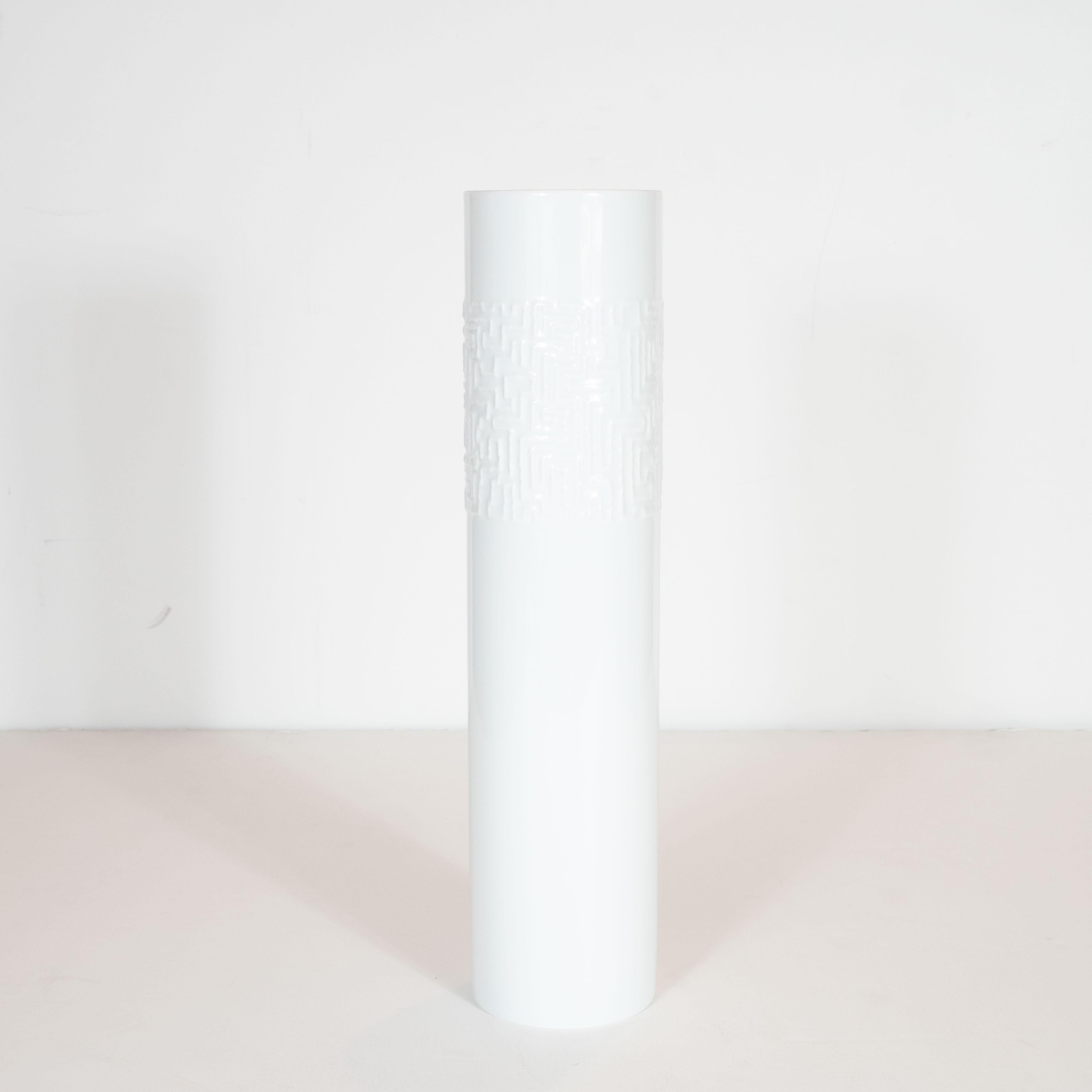 This elegant and understated vase was realized by the esteemed maker Rosenthal, circa 1980. The piece offers an austere cylindrical silhouette with a wide band of raised abstracted Brutalist hieroglyphic inscriptions. With its monochromatic palate